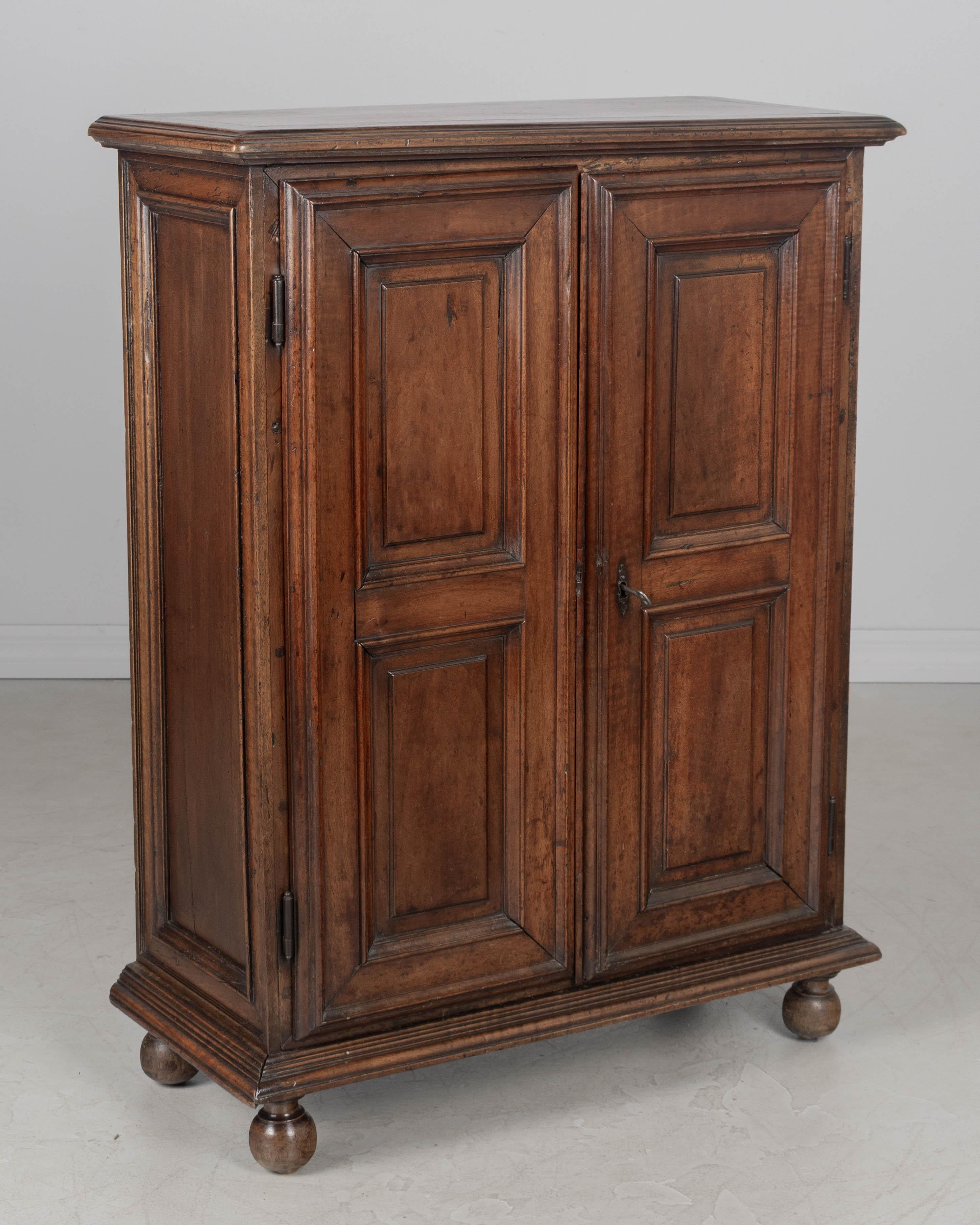 Armadio francese del XVIII secolo in stile Luigi XIII, realizzato in noce massiccio con due ante a pannello rialzato. L'interno è dotato di due ripiani, di cui quello inferiore è regolabile. Ferramenta in ferro. Serratura e chiave funzionanti.