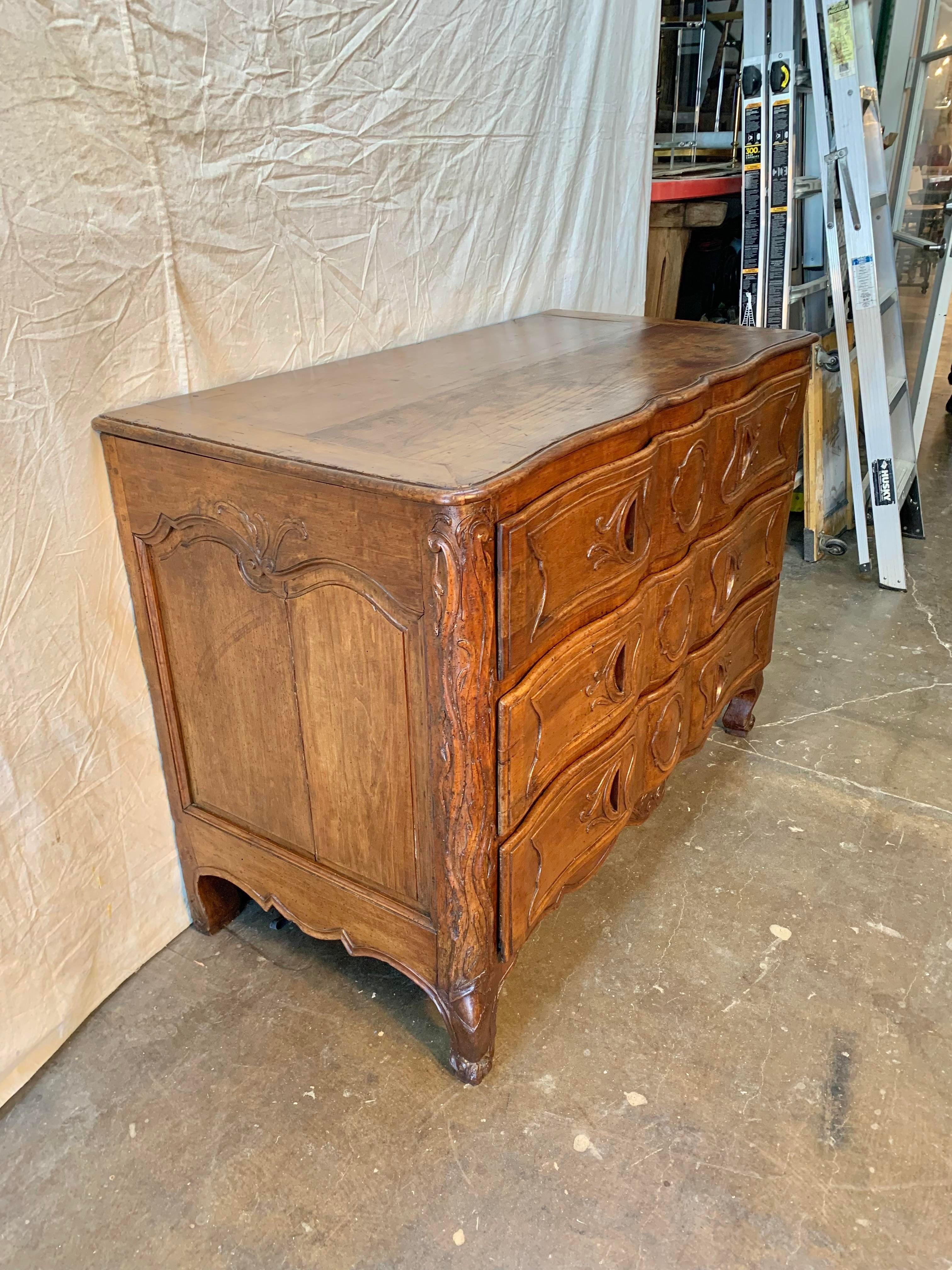 Found in the South of France, this exceptional 18th century French Commode was handcrafted and carved by talented artisans from solid old growth walnut. The piece features a two plank top that has been banded on each end with a carved serpentine