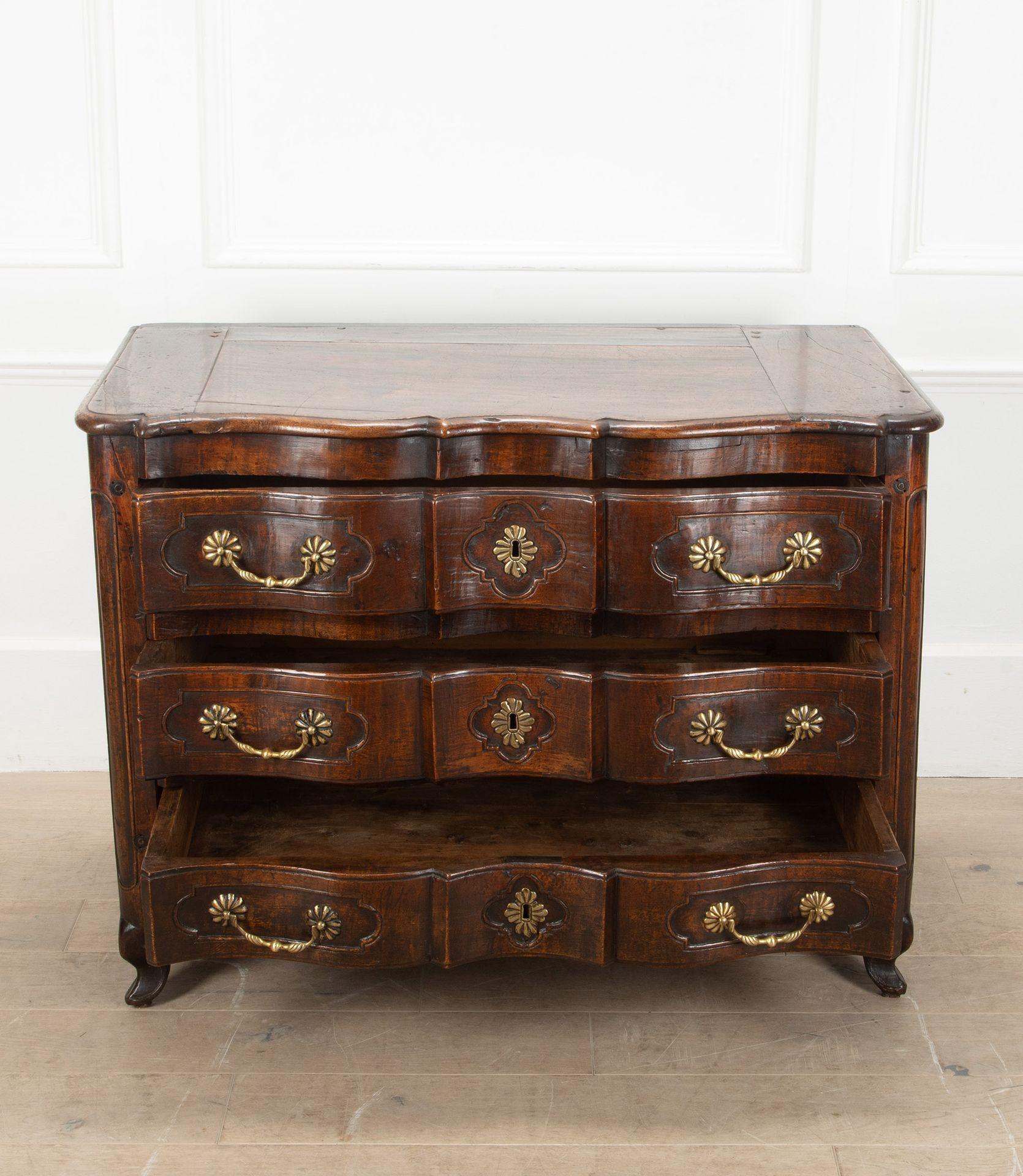 A really good example of an 18th Century French walnut commode from the Louis XIV period.
With arbalète shaping to the front and having three drawers with original brass handles.
Featuring scalloped cartouches to the drawer fronts and carved snail