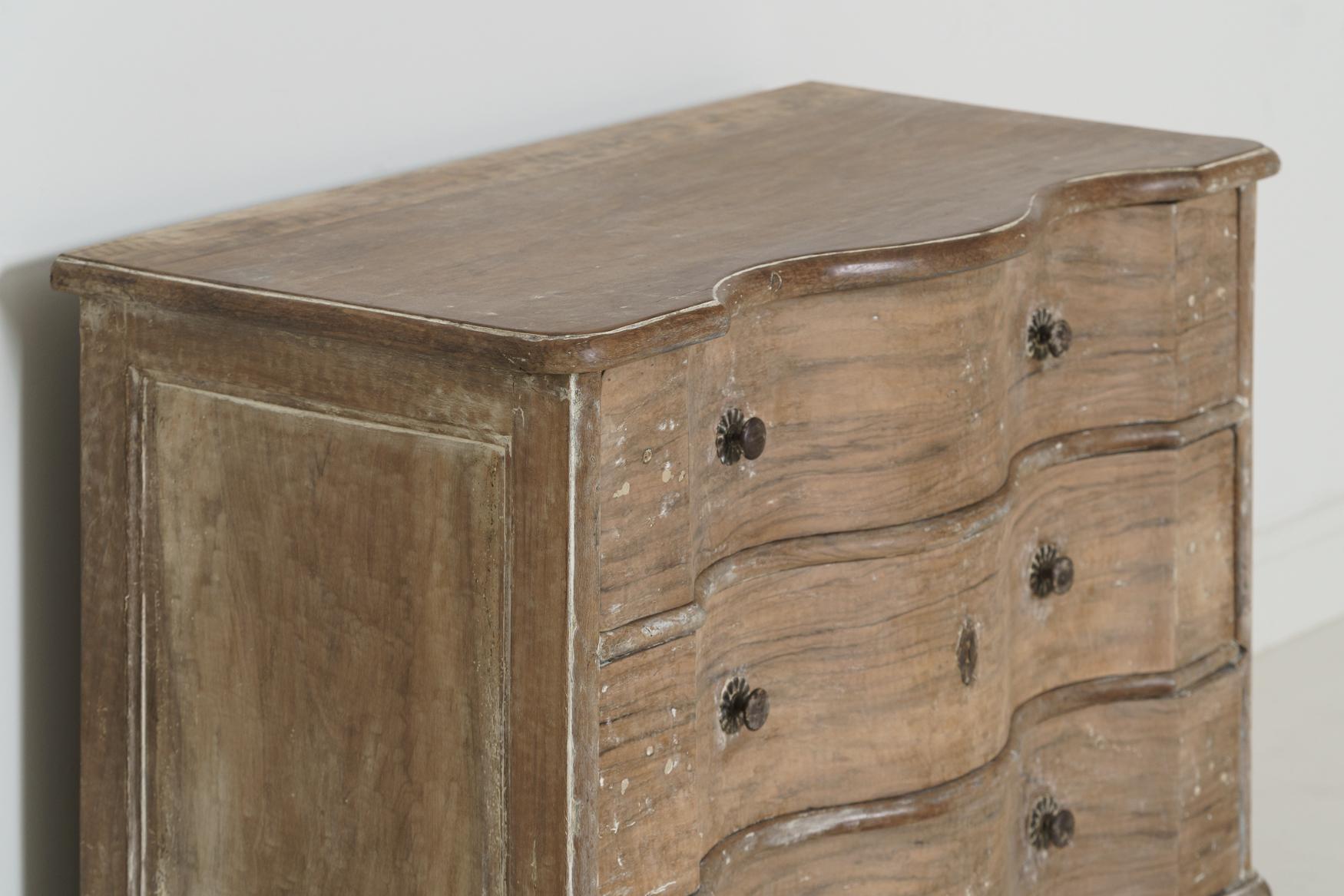 A beautiful chest of drawers with serpentine front, original hardware, bun feet, and raised, paneled sides. The patina is natural walnut with traces of original paint. Found in Provence, France.