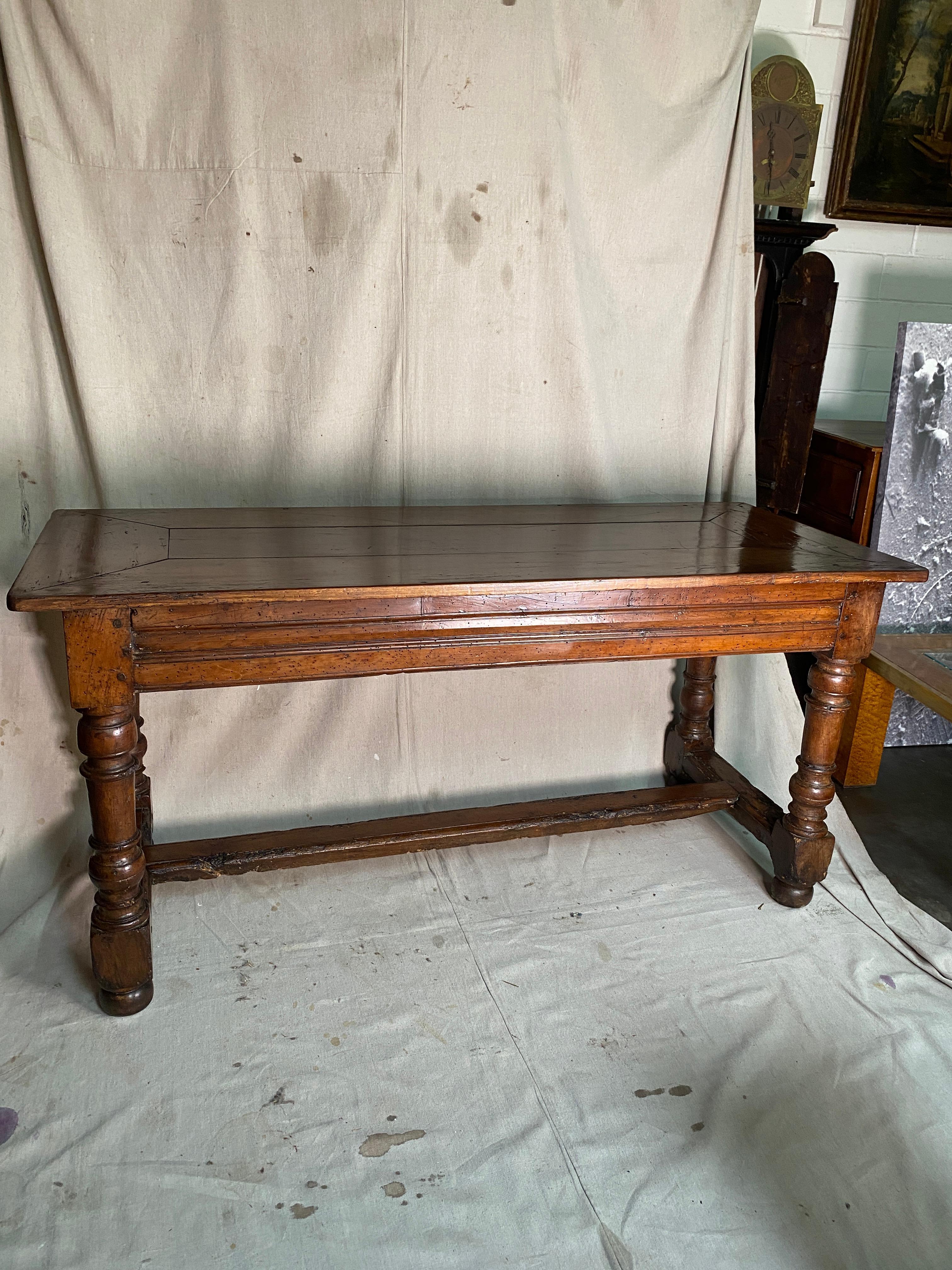 French Country table with 4 turned legs. Joined with a stretcher on center.
Top has an enveloped shaped wood frame top. 
Has a wonderful color and patina.