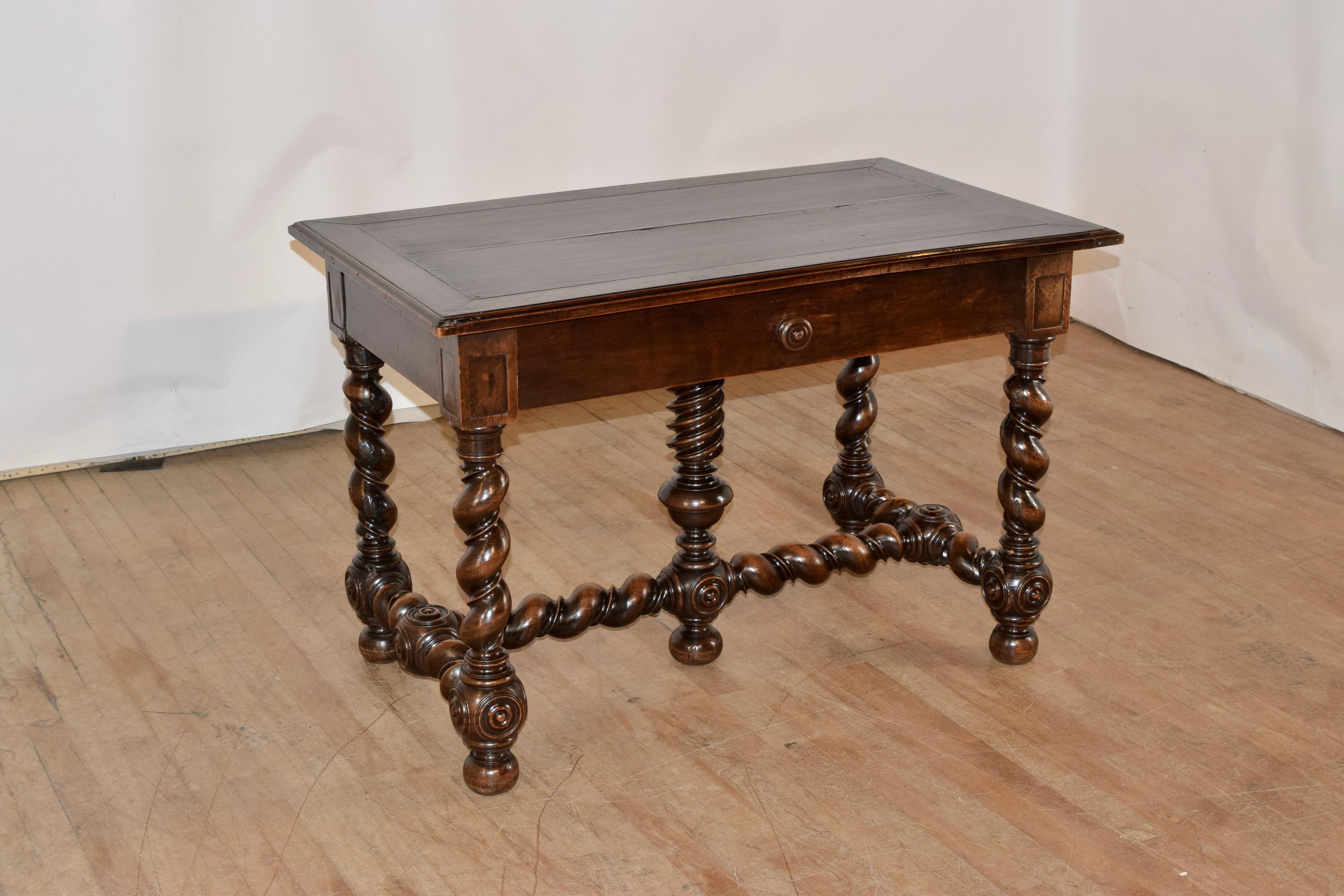 18th century walnut library table from France. The top is made from two planks and is banded with a beveled edge, following down to a simple apron, which contains a single drawer in the front. The table is supported on hand turned barley and vine
