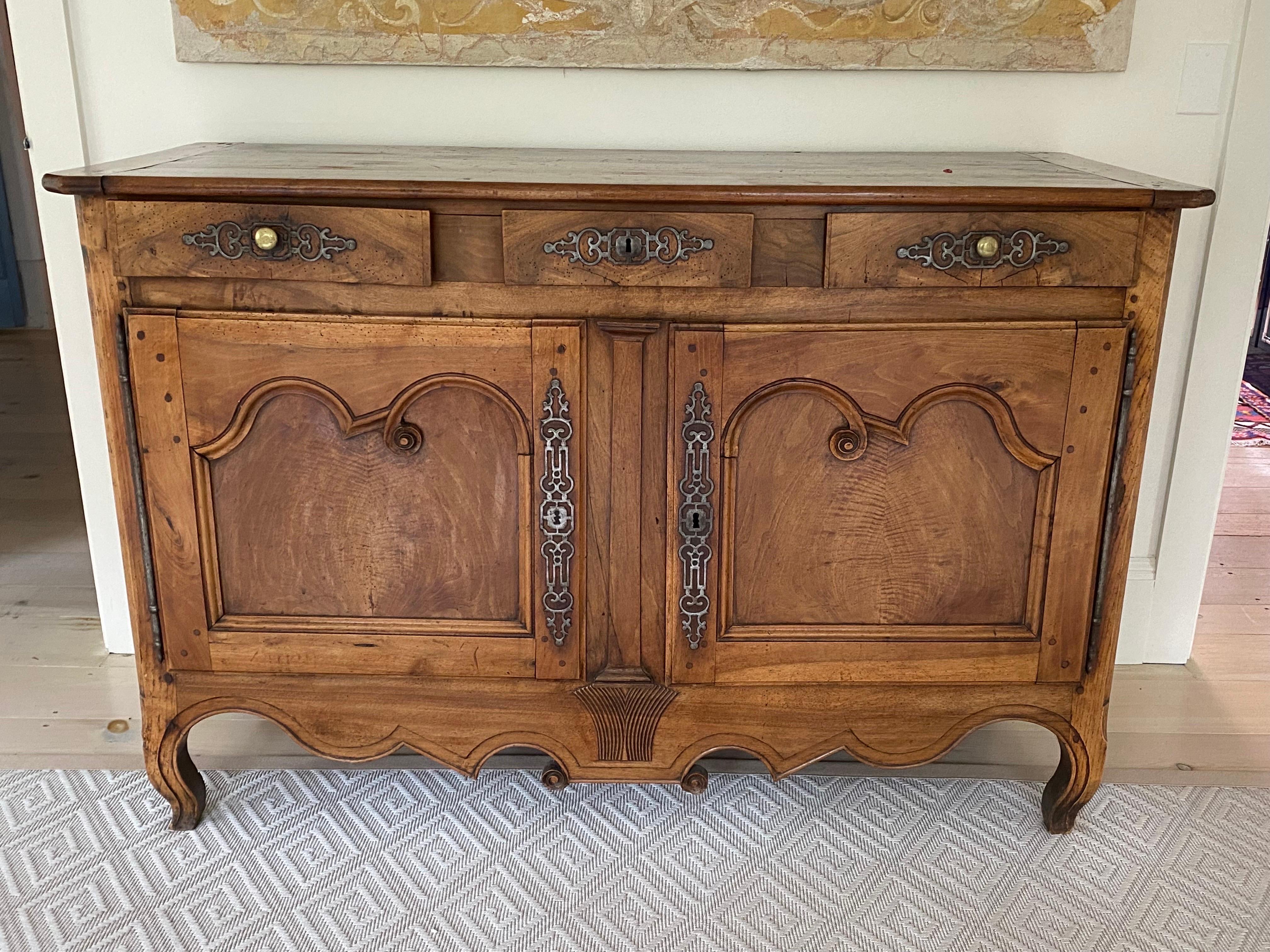 18th century French walnut Louis XV Provincial Buffet
A period handcrafted buffet made of solid walnut with three drawers above two beveled doors opening to a single shelf open. Original interior and exterior hardware. Classic curved and scrolling