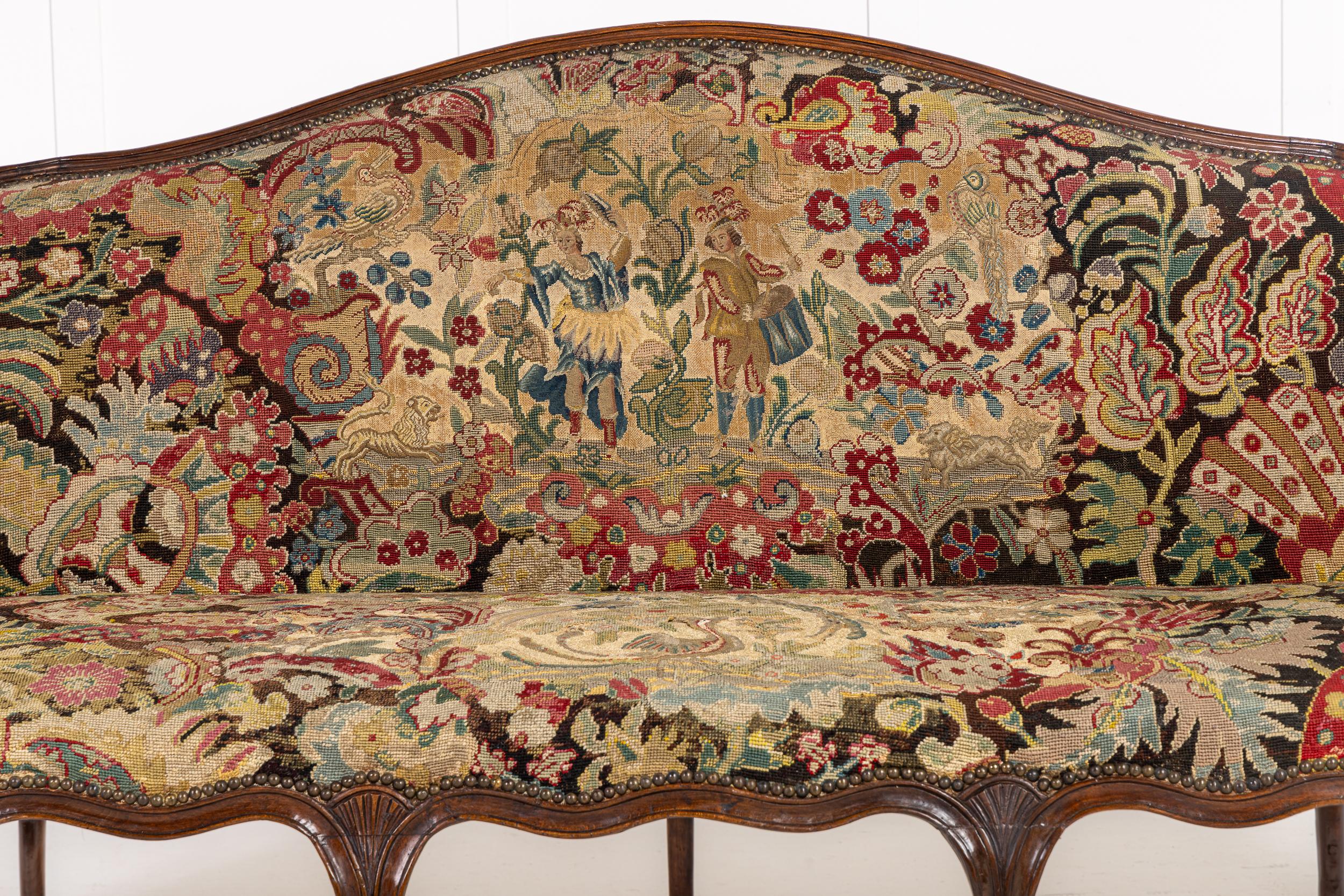 Ein französisches Nussbaumsofa aus der Mitte des 18. Jahrhunderts, gepolstert mit außergewöhnlicher Handarbeit.

Dieses schöne, formschöne Sofa mit seinen neun Cabriole-Beinen, der Kamelrückenlehne und den fein geschnitzten Serpentinenschienen und