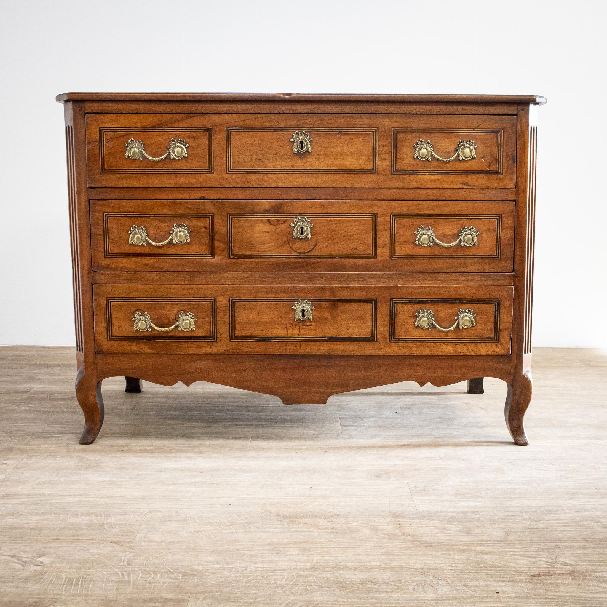 A beautiful piece of furniture, this 18th century walnut commode in the Louis XV style has the character and patina of long use. The three drawers have some lovely inlaid stringing on the fronts suggestive of three panels on each. It has cabriole