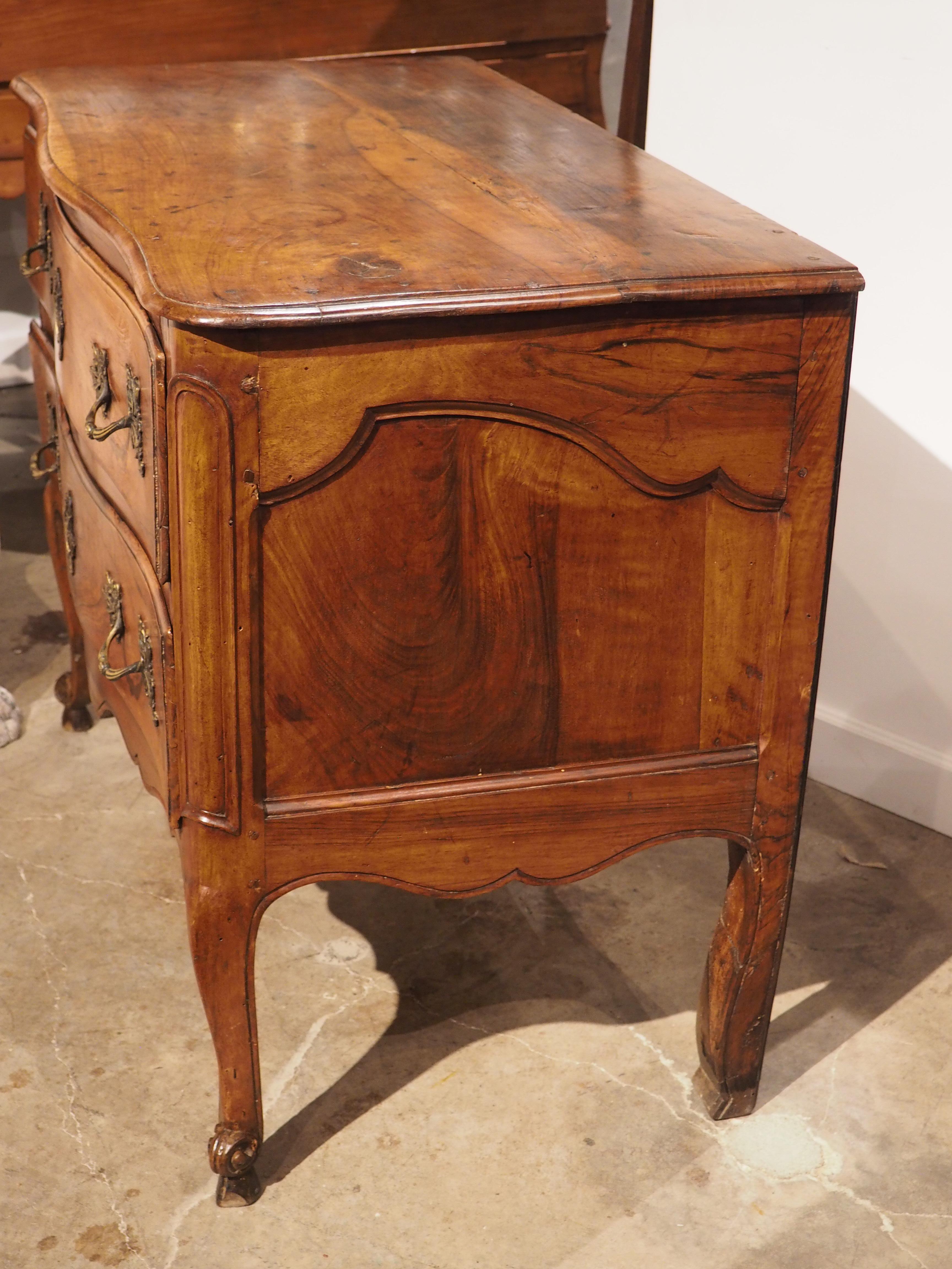 Known as a commode sauteuse, this walnut chest of drawers was hand-carved in France in the 1700s during the reign of Louis XV, making it a period piece. Notice the long, curvy cabriole front legs (the back legs have a more subtle contour) beneath a