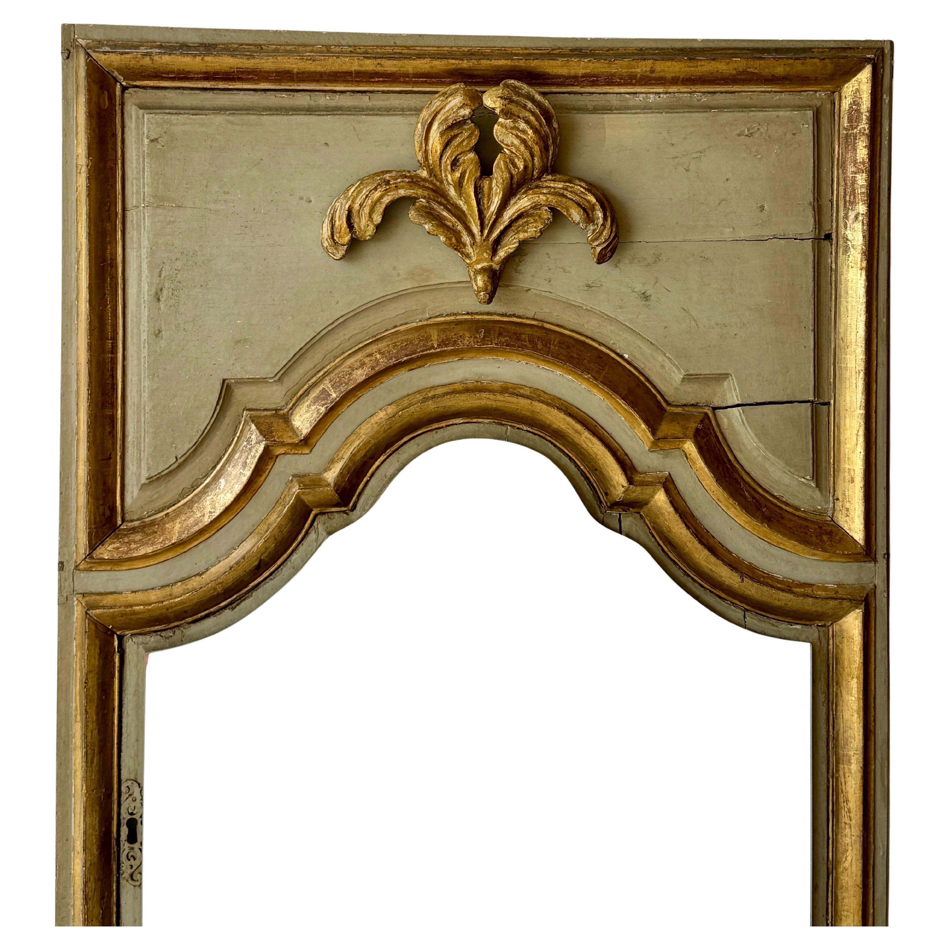 This large scale French armoire door was repurposed into a one of a kind floor mirror with mirror-glass being added at a later date. This charming wooden floor mirror with its original paint and gold gilding is a fantastic statement piece on when