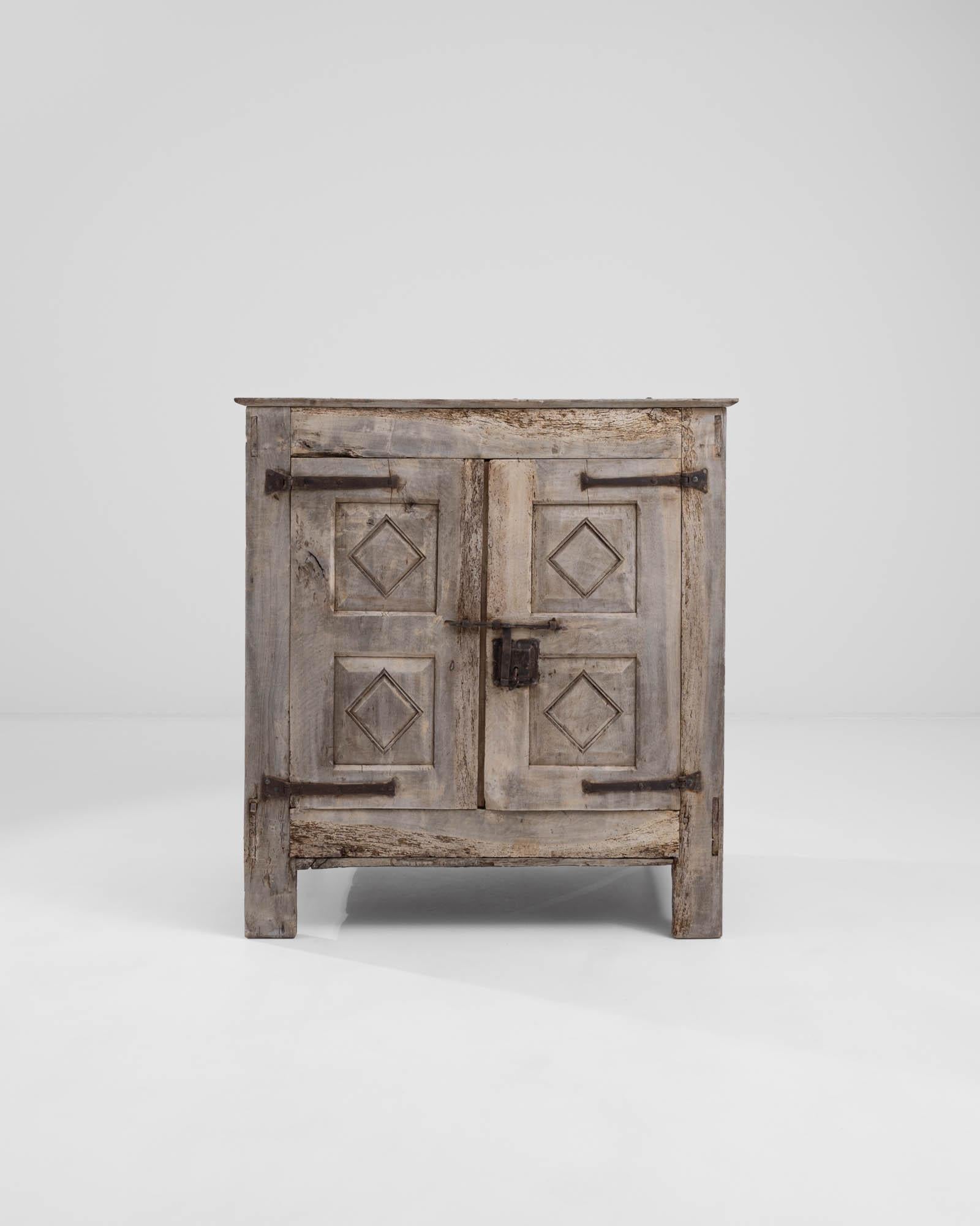 A rustic wooden cabinet from 18th century France. The elaborate metal keyhole and wrought iron hinges, speckled with a mesmerizing patina convey a deep sense of history and the trappings of this drawer’s experience. With a countervailing effect, the