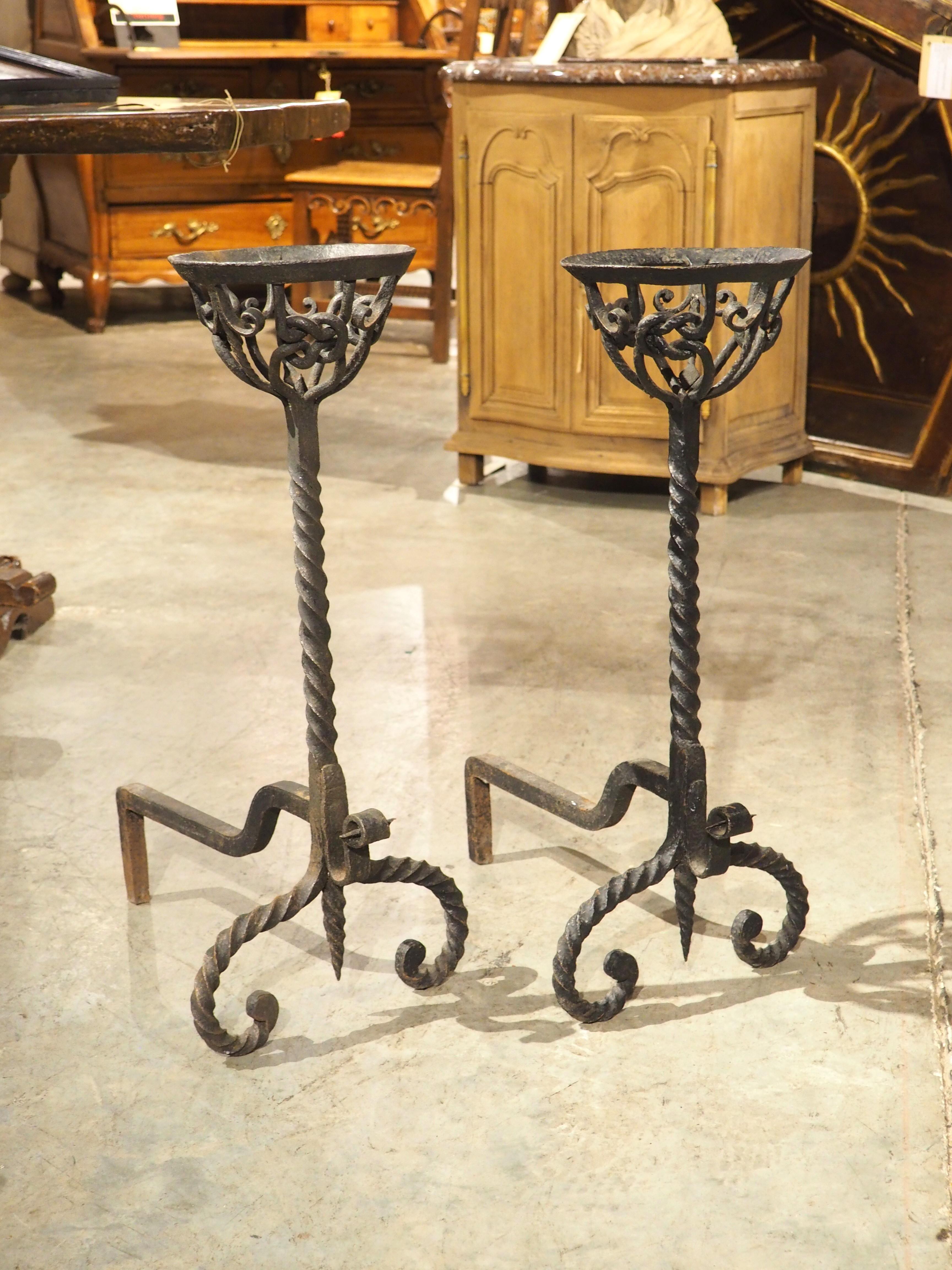 Un par de chenets de hierro forjado asombrosamente detallados, estos primitivos utensilios de cocina se habrían encontrado en la chimenea de un castillo francés en el siglo XVIII. A veces llamados andirones, los chenets como éste, con un cesto