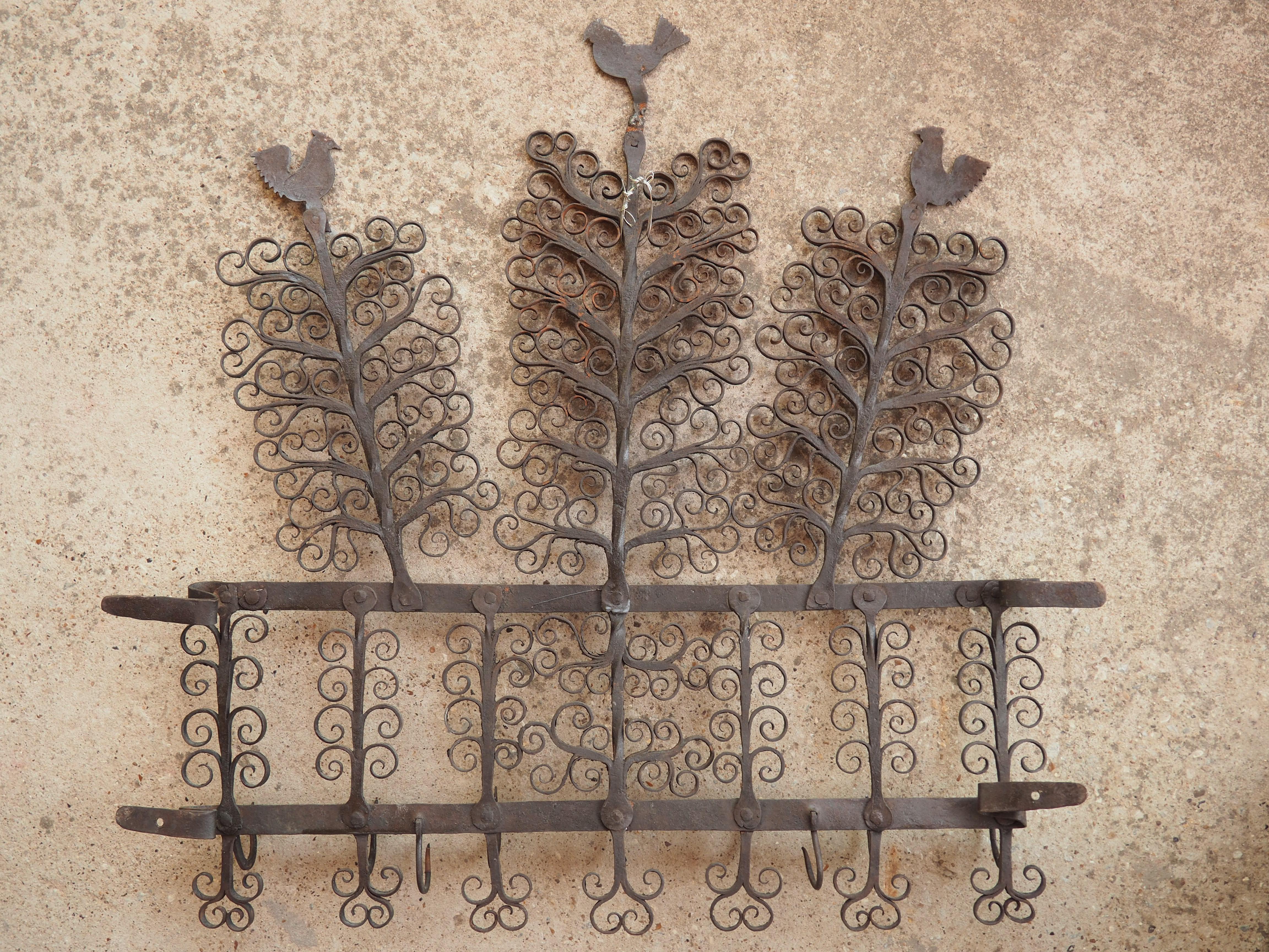 Known as an archelle, this wrought iron kitchen hook rack has rooster and volute scroll motifs. Archelles were hung on the walls of kitchens or service rooms, typically in Northern France and Flanders. The hooks would be used to hold utensils,