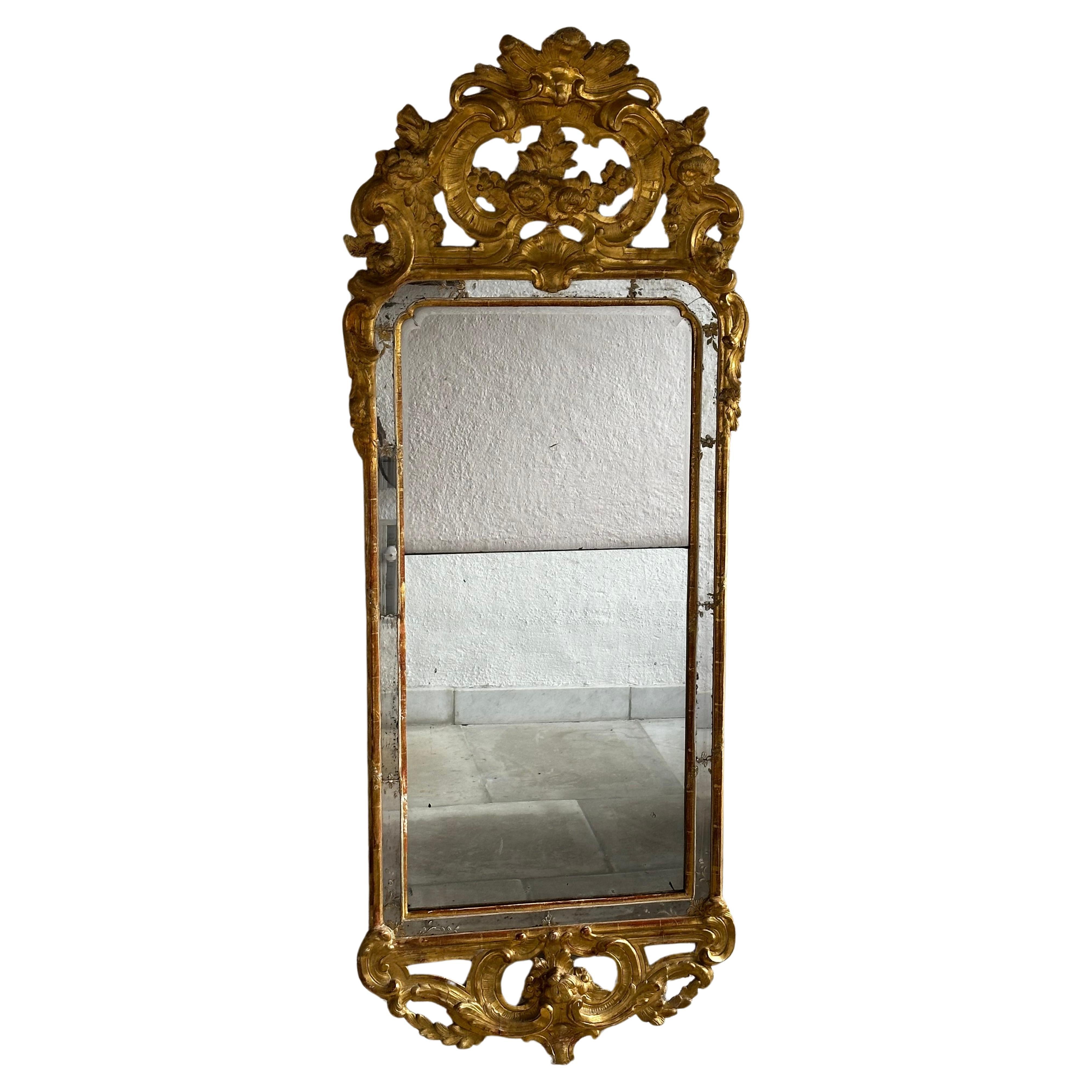 Ein großer Spiegel, der Johan Åkerblad zugeschrieben wird, nicht signiert. Er war ein Spiegelhersteller in Stockholm von 1758 bis 1799. Dekoration aus Pappmaché. 
Der Deckel ist mit Akanthus, Rocaille und Voluten verziert.