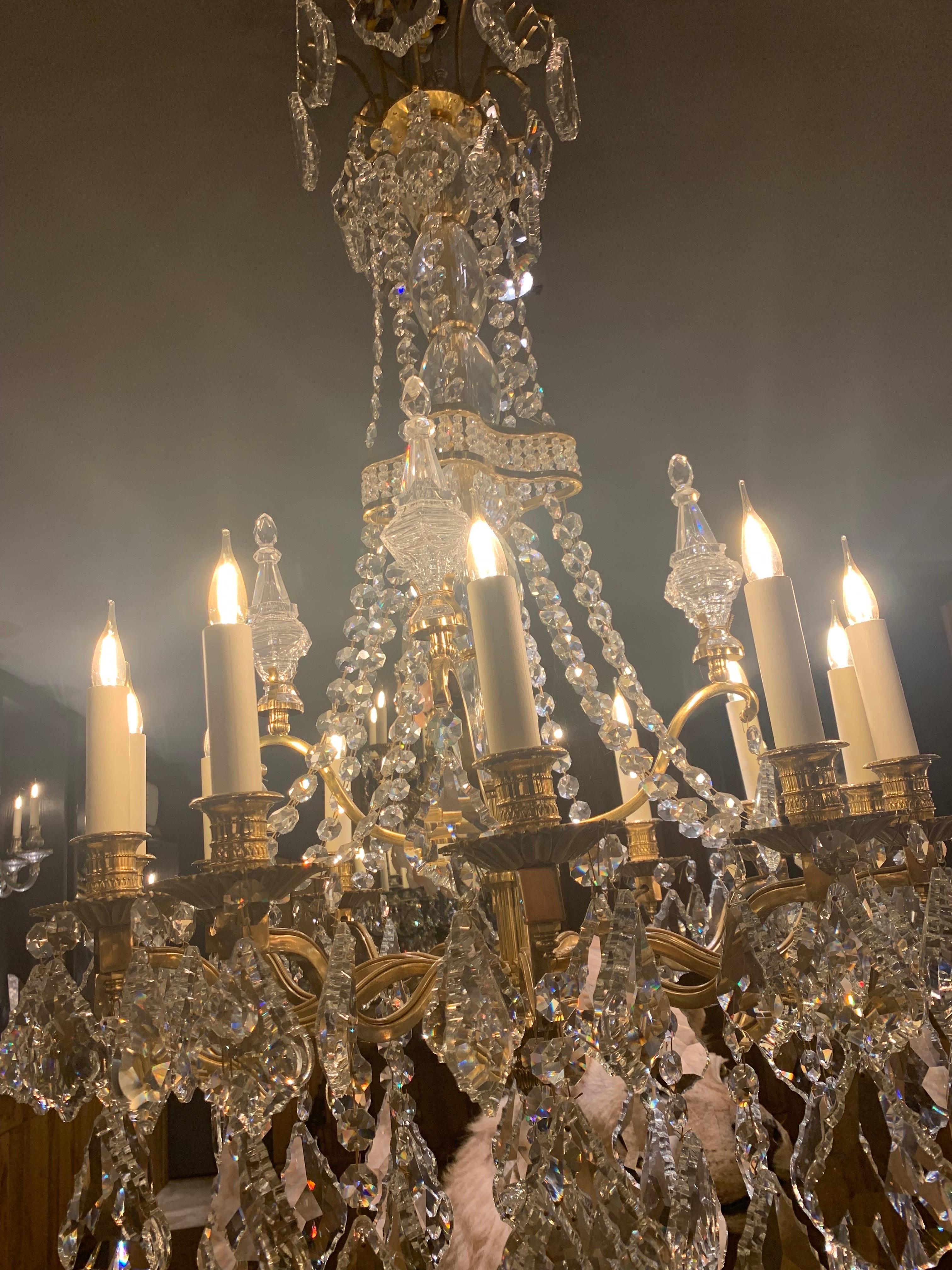 Magnifique lustre galerie de style louis XIV à 12 bras de lumières en bronze doré 18 carats. 
Le lustre est décoré de pendentifs en cristal et de pièces en cristal taillé.

Nous avons un lustre en stock mais nous pouvons les produire sur mesure