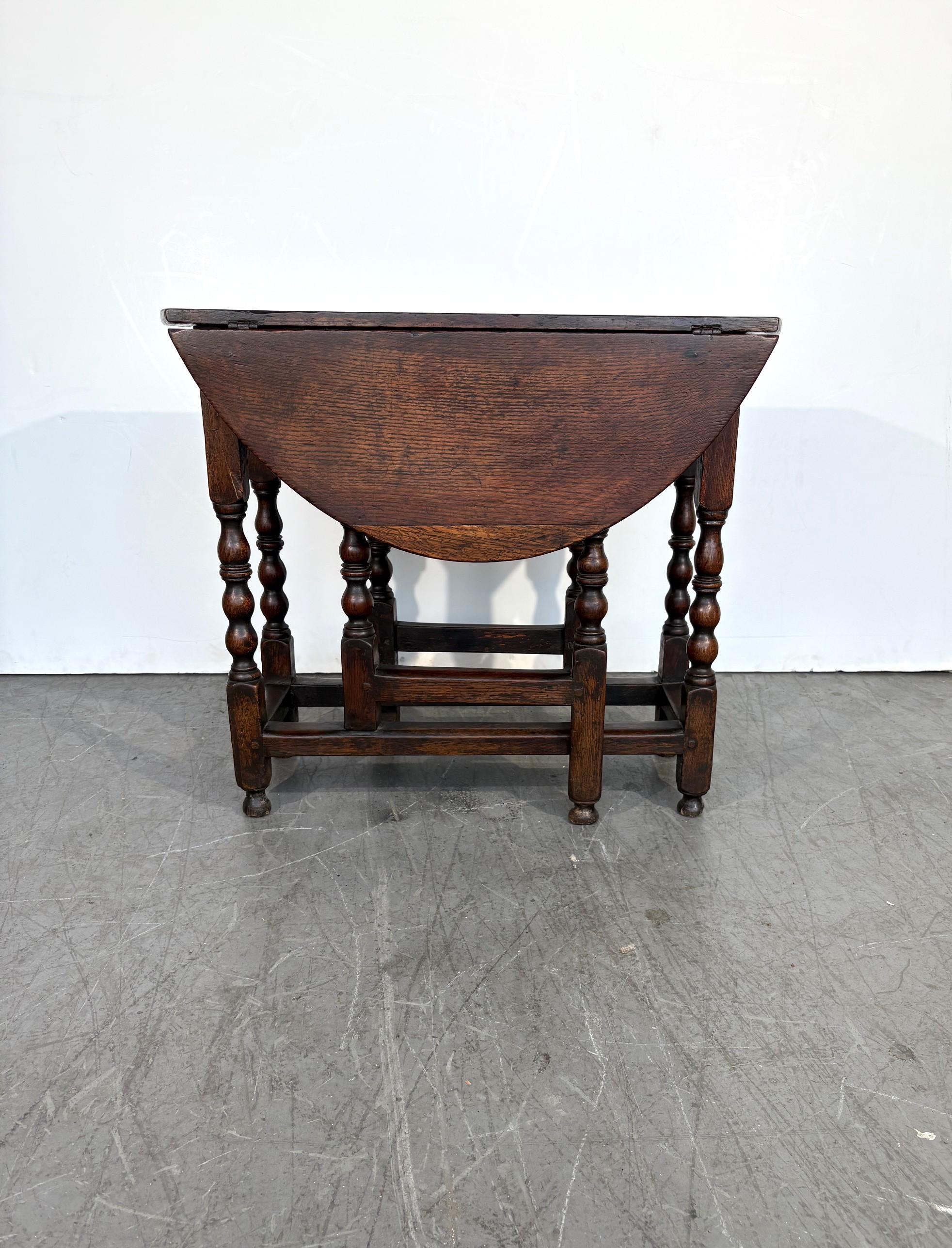 Une table à pied de porte ancienne.   Une table Gateleg avec une construction en chêne massif et des goujons. Jambes tournées au fuseau. Début du XVIIIe siècle C.C.C.

