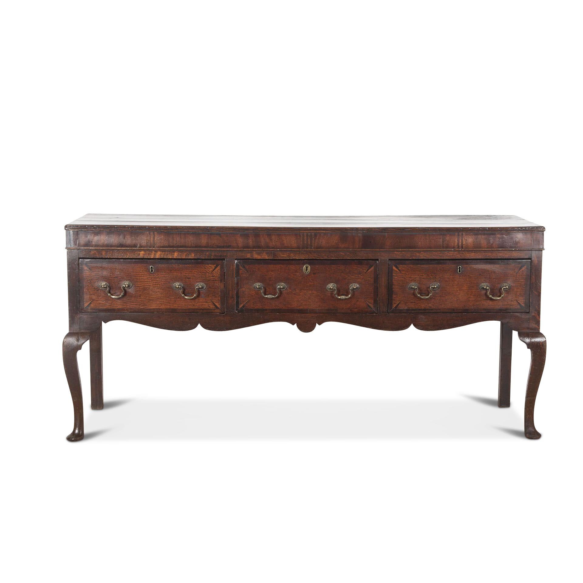 18th Century oak dresser, the moulded top with a mahogany inlaid frieze above three mahogany crossbanded drawers with brass swan neck handles and a shaped apron below, raised on cabriole legs with pad feet. In good condition and colour. Circa