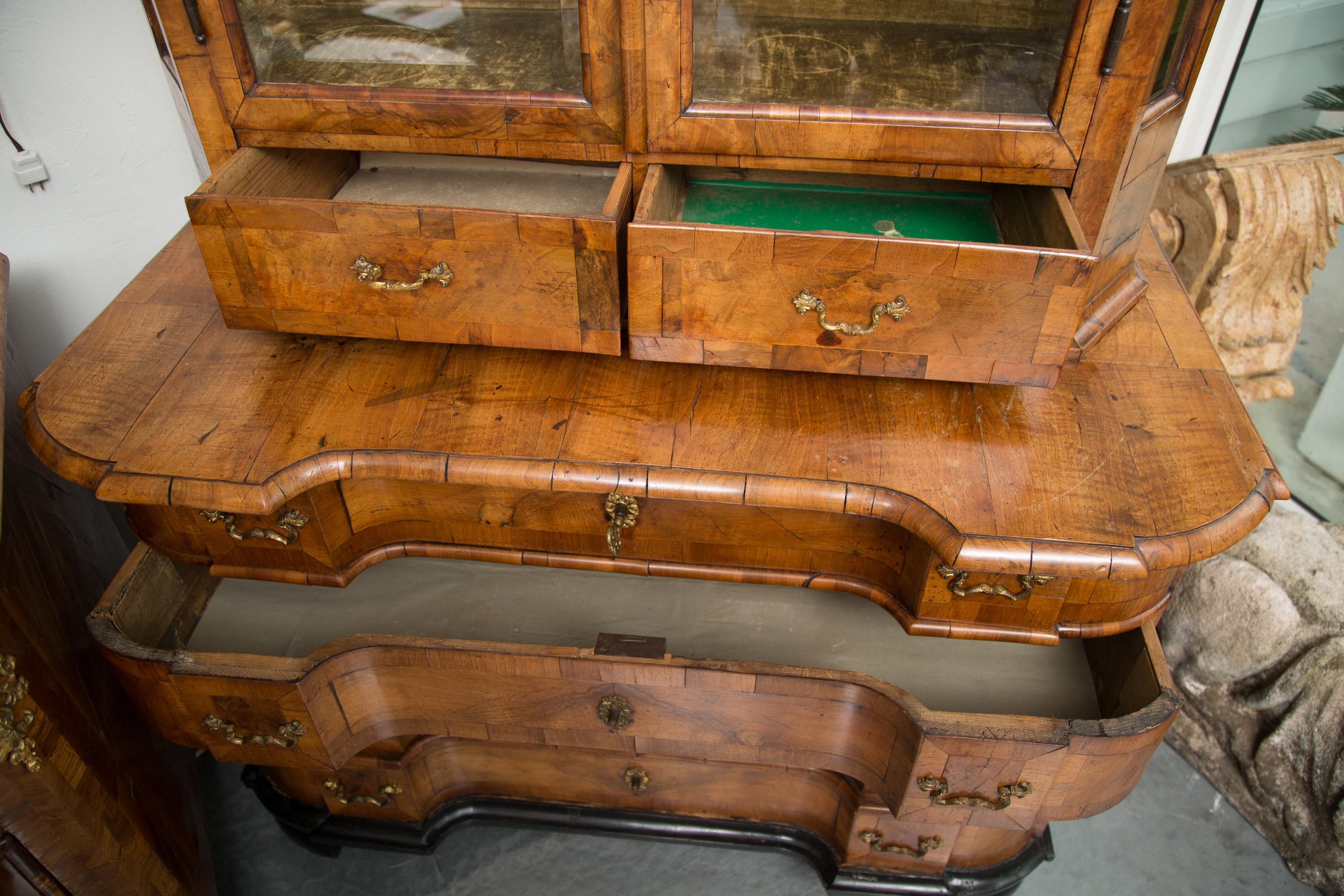 This is a very mellow George i burled walnut cabinet. There is a double domed cornice with ogee moulding over conforming top with two deep beveled glass doors and canted corners also with glass insets. The breakfront bottom has four long graduated