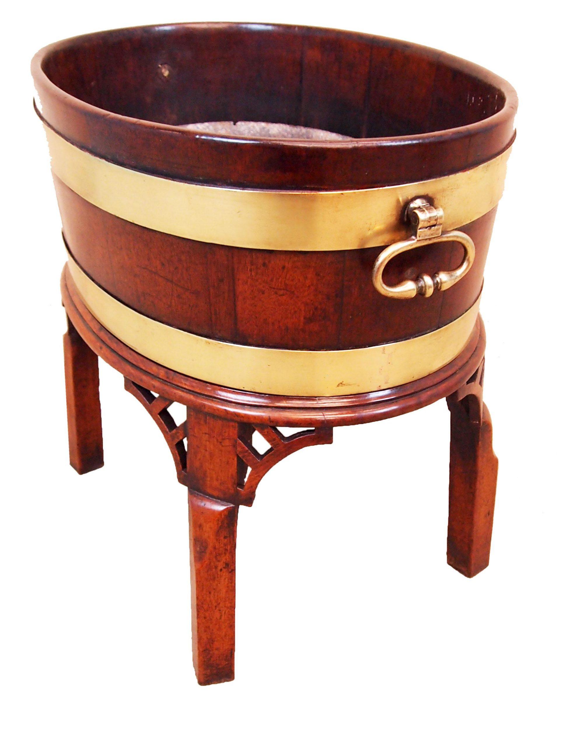 18th century (George I) English mahogany oval open wine cooler with original brass bound decoration and original brass carrying handles resting on its original square legs stand with pierced corner brackets.
     