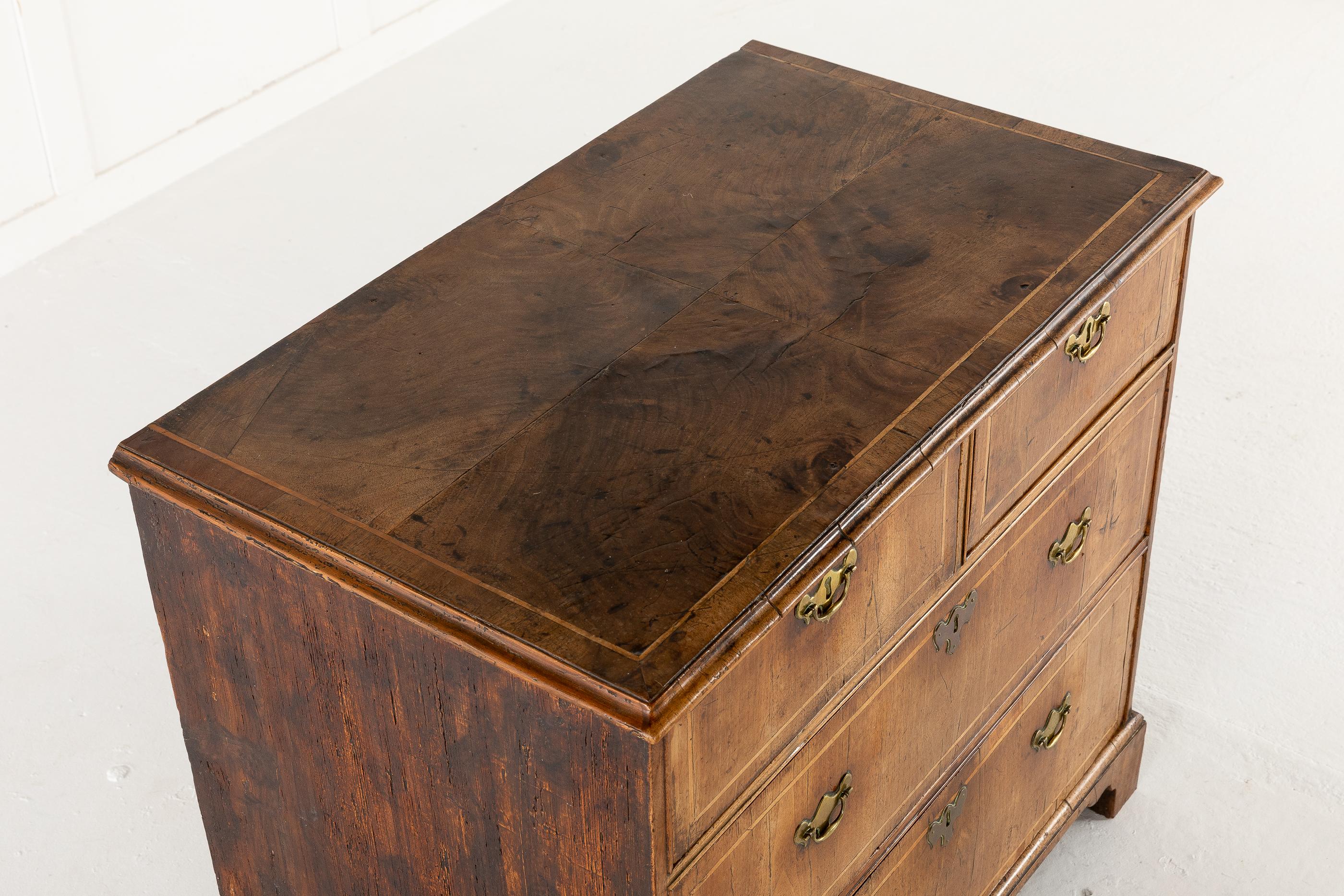 18th century, George I, Pine sided, veneered walnut chest of two short drawers and two long drawers. Retaining all its original metalwork. Having a wonderful faded colour and patina. With a quarter veneered top and standing on carved bracket feet.