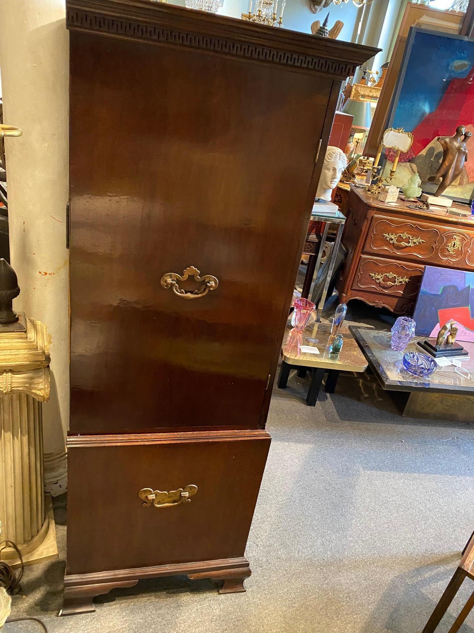 the reverse ogee moulded cornice and stylised Greek key frieze above a pair of shaped fielded doors with acanthus carved moulded borders, enclosing three linen slides, over two short drawers, with two long graduated drawers below, on shaped ogee