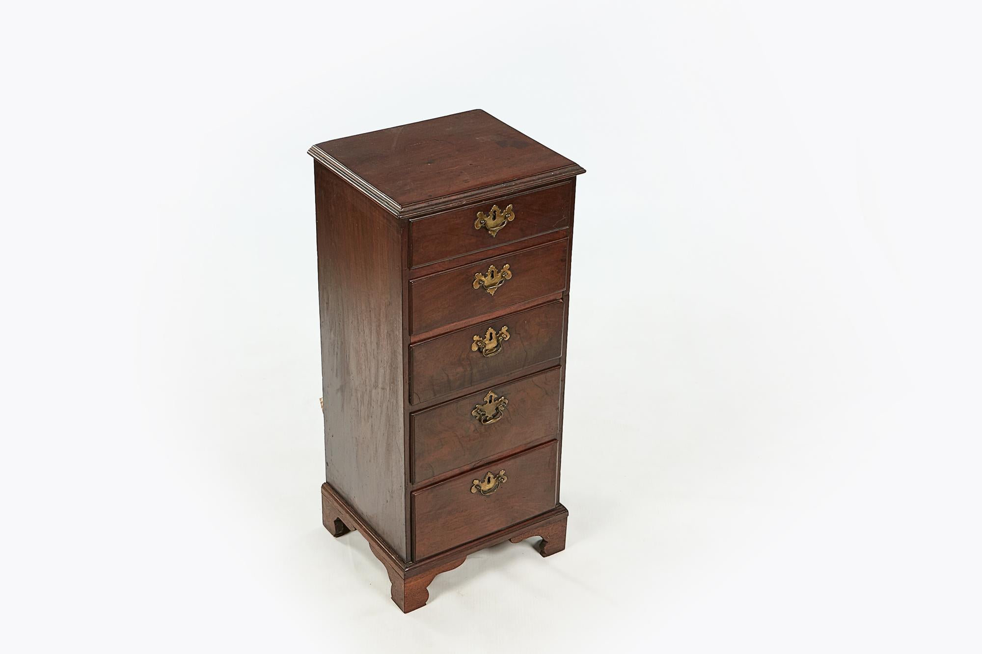 18th century George II flame mahogany miniature tallboy, the moulded top over five graduated drawers with brass pulls with integrated escutcheons terminating on ogee bracket feet.