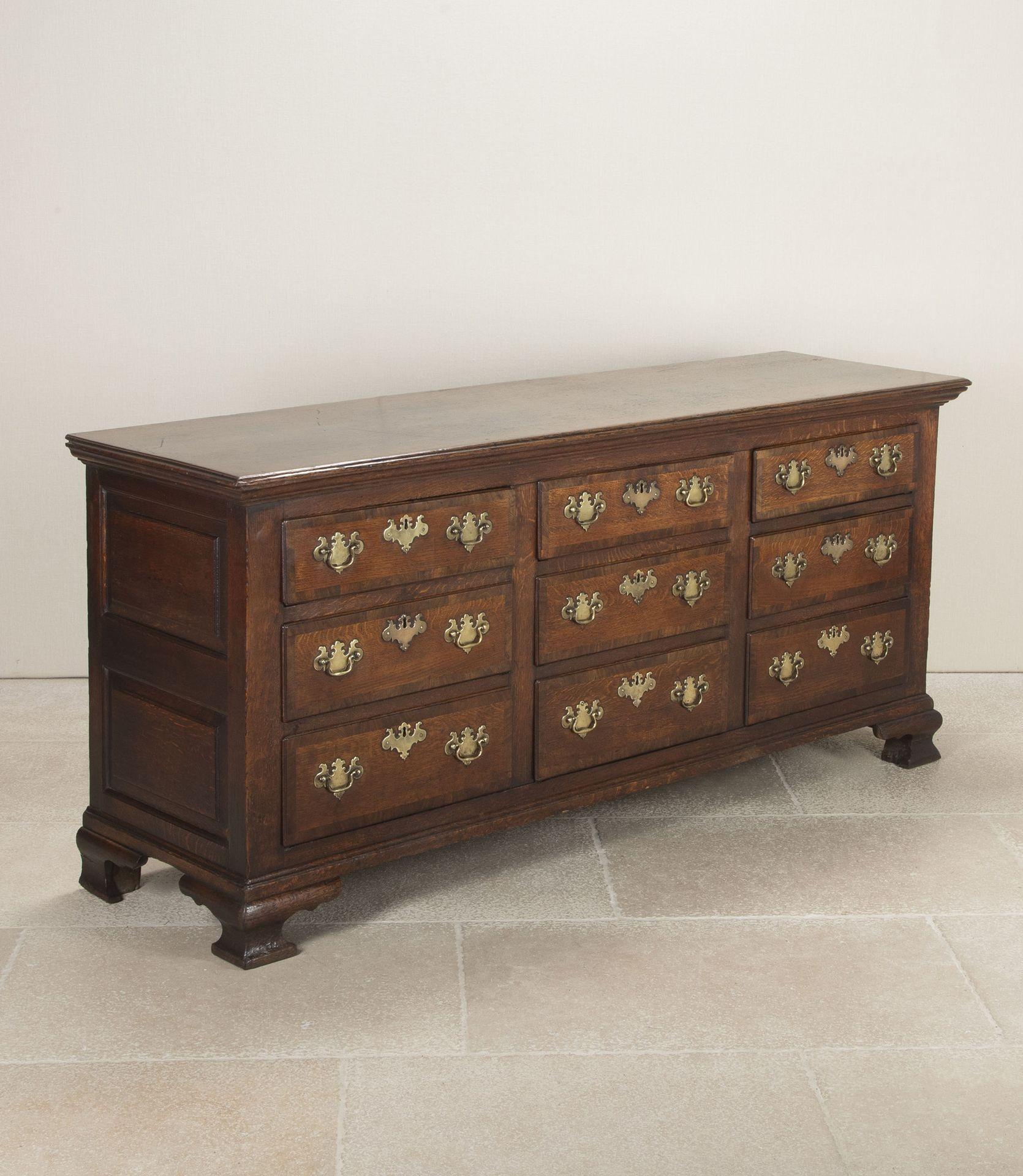 18th Century Provincial English Country House nine drawer dresser base from the George II era.In oak with the drawers cross banded in walnut with its original brass hardware. With some historic repairs but retaining its original locks standing on