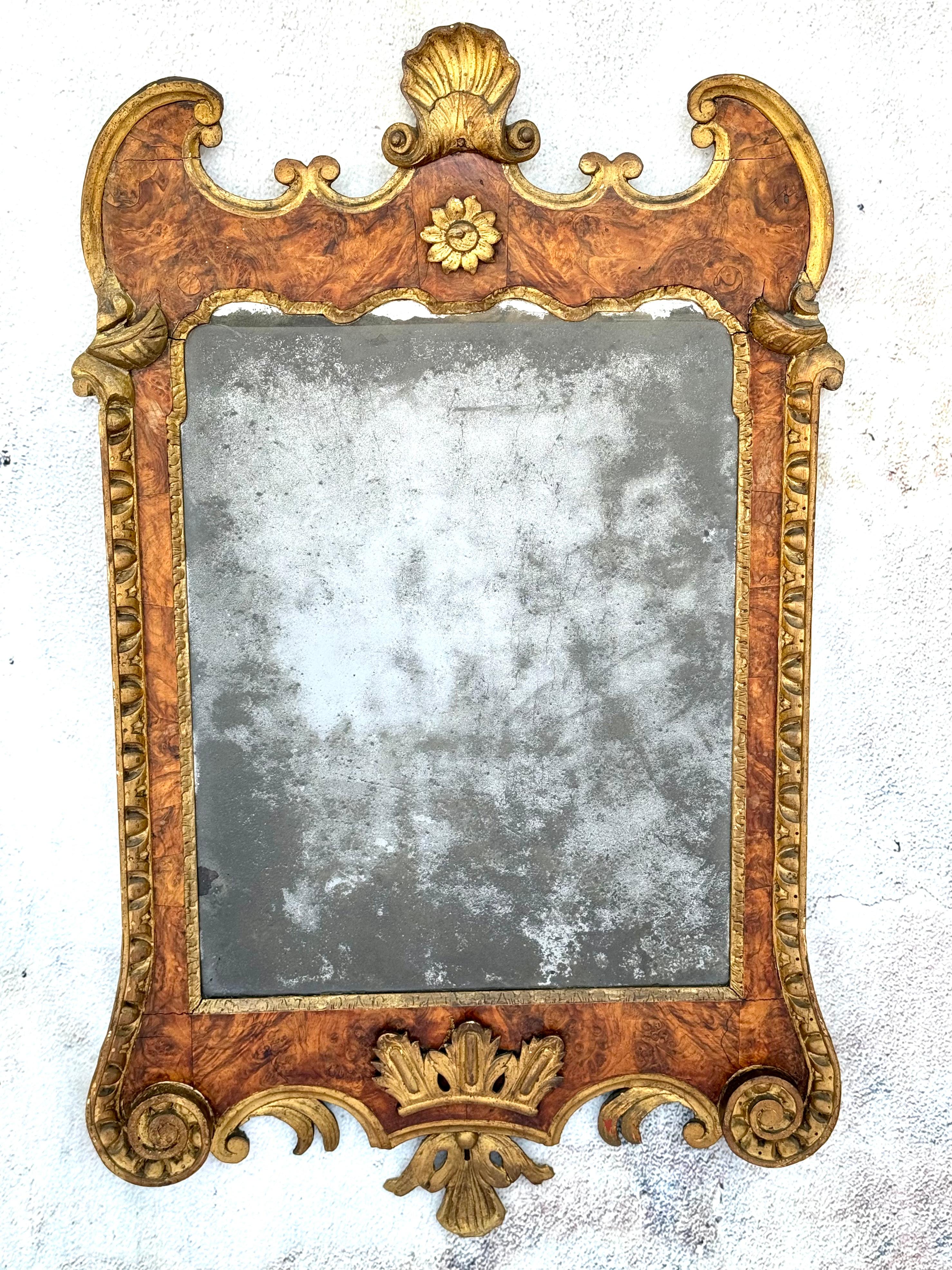 Un beau et impressionnant miroir géorgien du XVIIIe siècle en bois doré et ronce de noyer. Le cadre en noyer est entouré d'une dorure ornementale et d'une crête festonnée. La partie inférieure est centrée sur une couronne en bois doré. Conservation