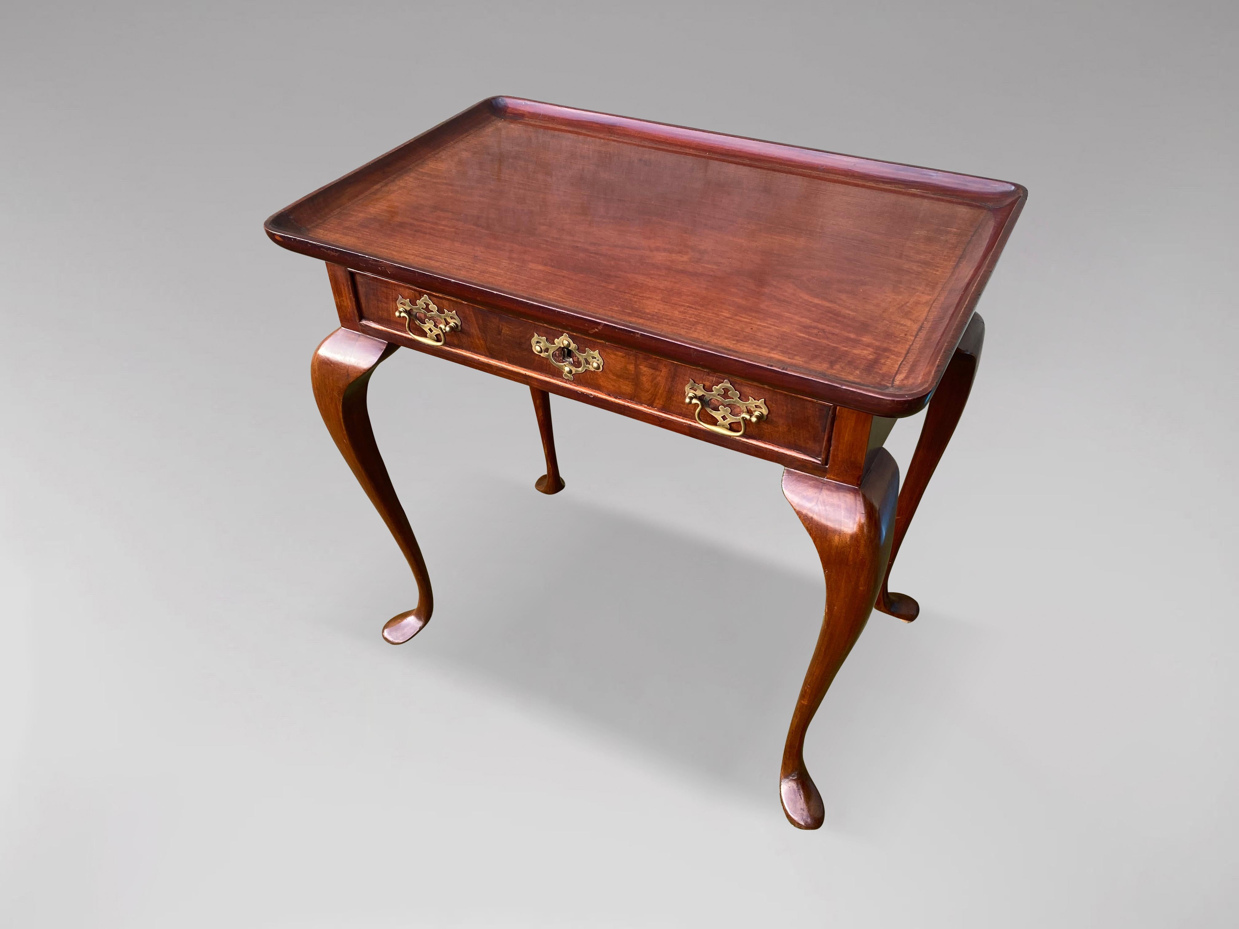 A very fine 18th century George II period mahogany tea table featuring rectangular dish top with raised moulded edges, plain skirts comprising one long single drawer with cock beading boarding and with a pair of later brass handles. Standing on very