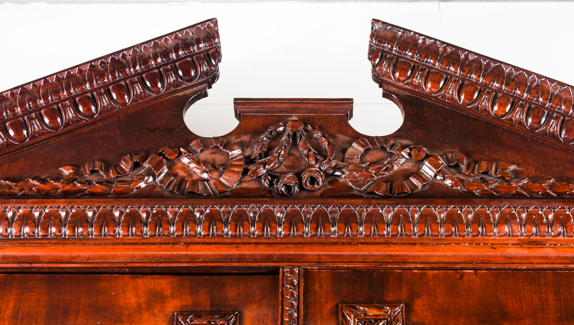 This is a fine antique flame mahogany ormolu mounted George III linen press, circa 1780 in date.

This exceptional quality linen press features a heavily moulded egg and dart cornice with a broken pediment and a centrally carved garland