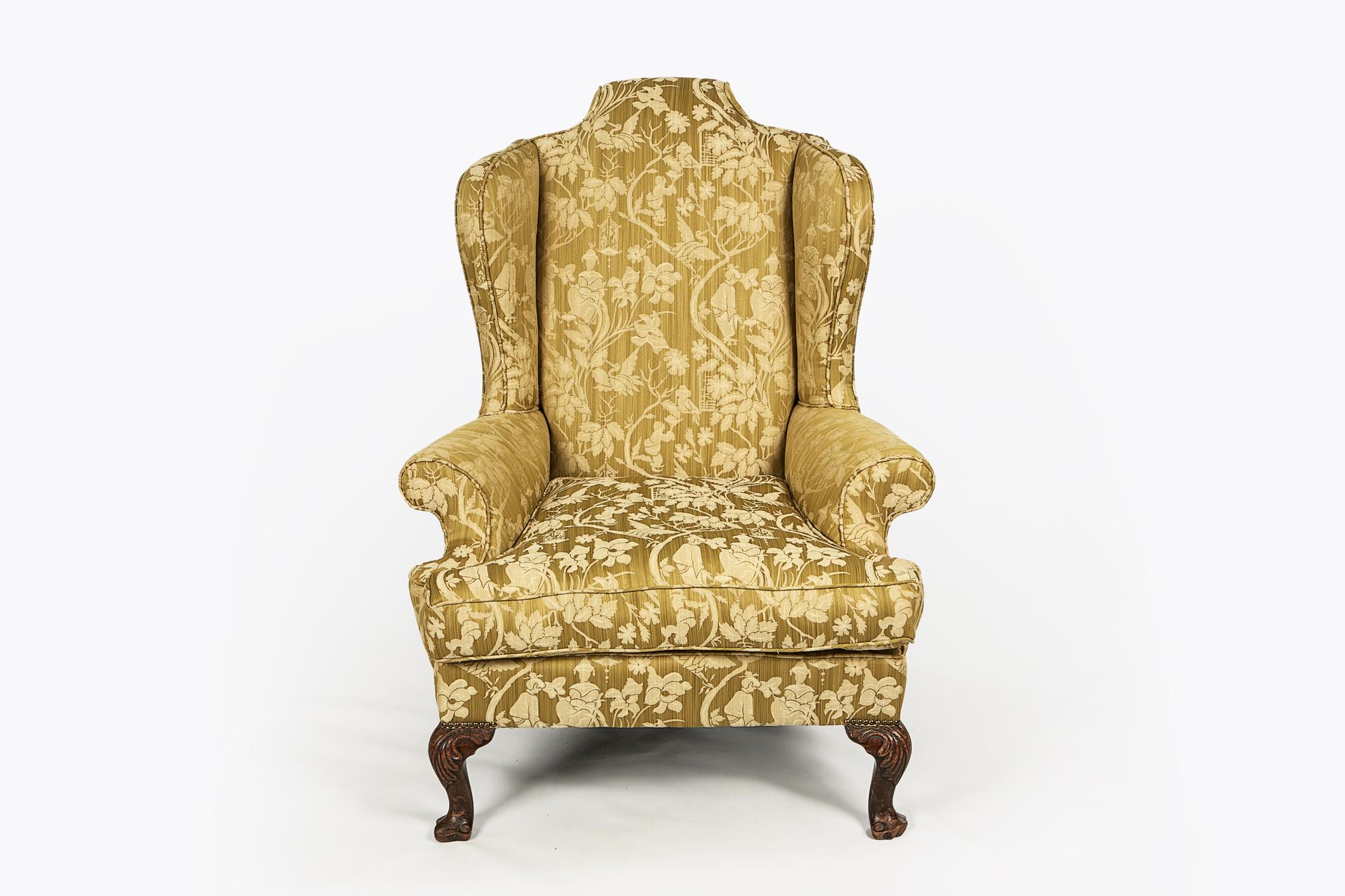 18th century George III Irish mahogany wing chair, the headrest of scroll form. Ornately carved scrolling foliate cabriole legs terminating on trifid foot.