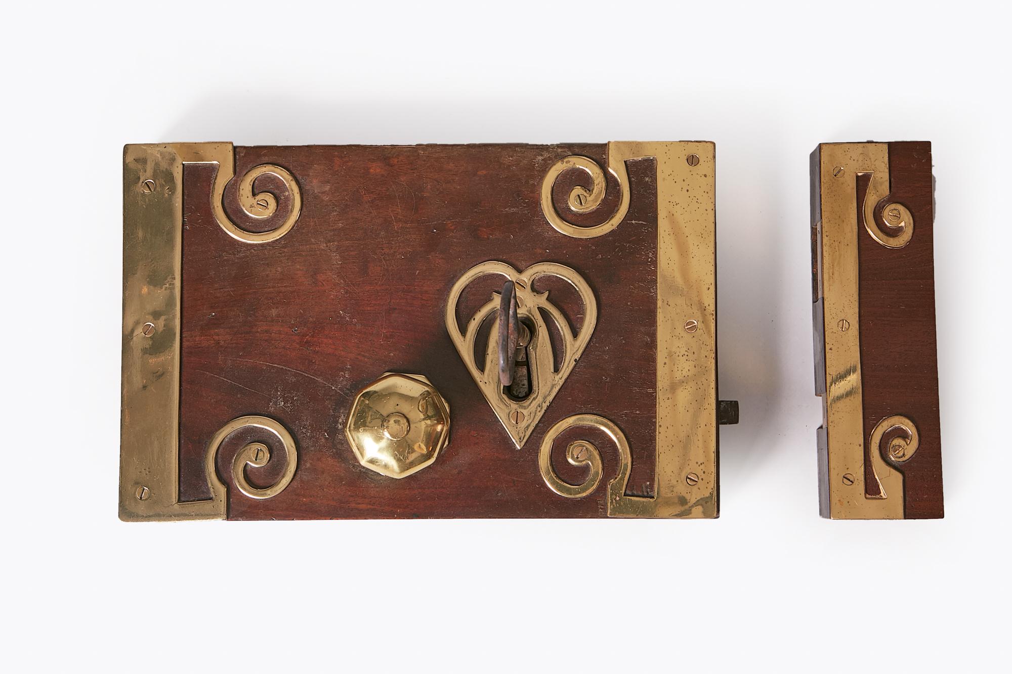 18th Century George III mahogany and brass bound door lock of large rectangular form with heart shaped brass escutcheon, original key, brass door knob and scrolling brass decorative detail throughout, circa 1790.