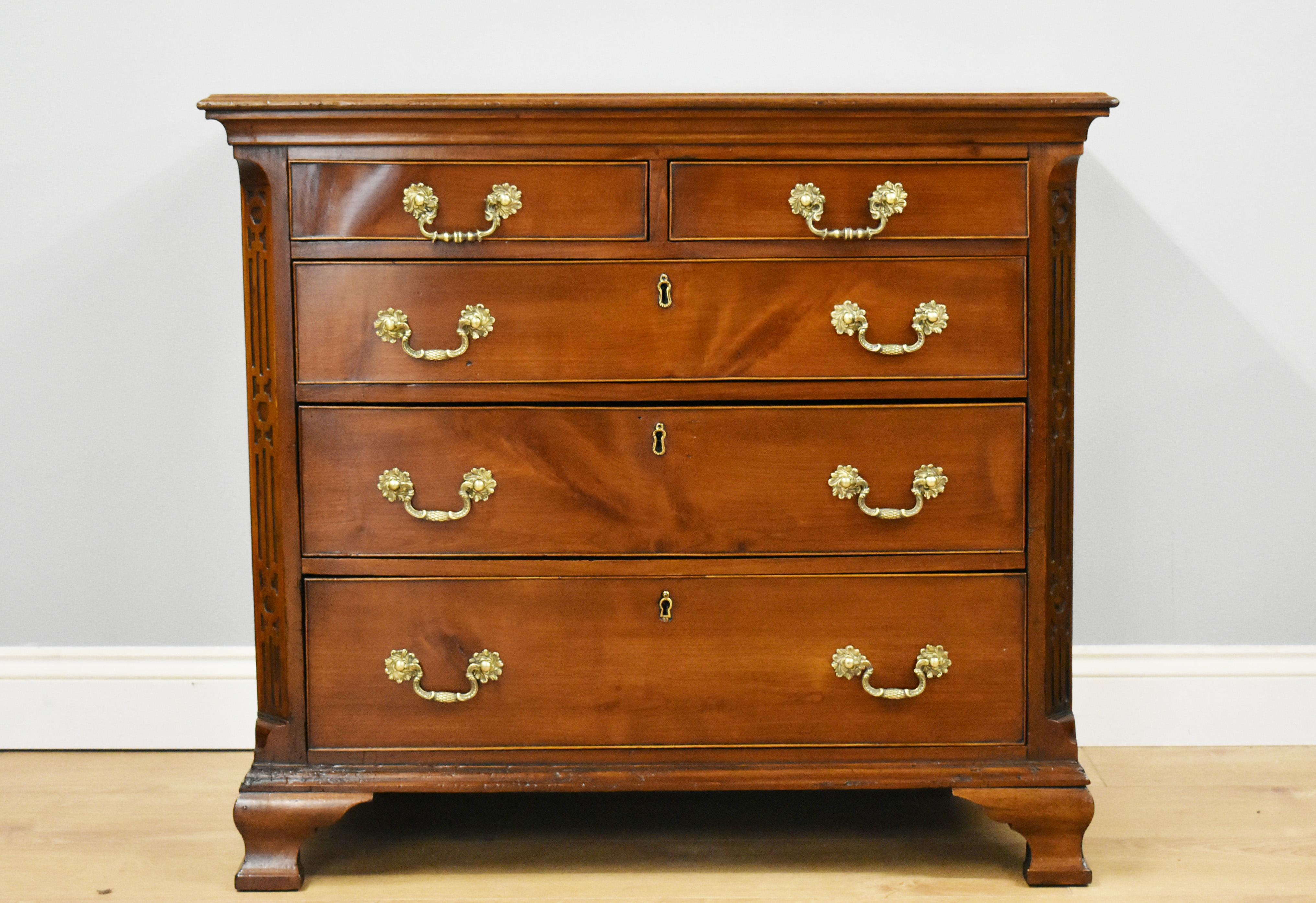 For sale is a good quality George III Mahogany chest of drawers of small proportions. Having two small drawers at the top, with three graduated drawers below, each with ornate brass handles. The chest has canted corners with blind fretwork