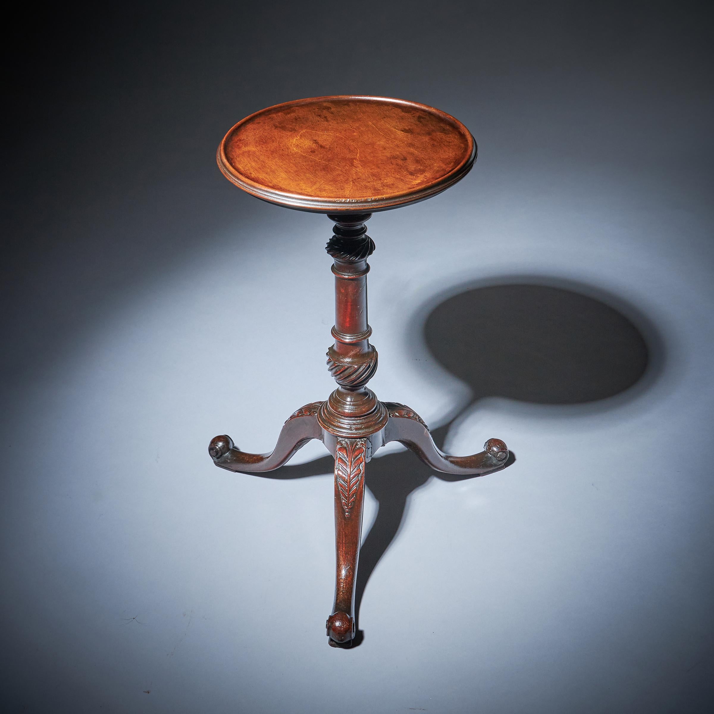 A beautiful George III kettle stand from the middle of the 18th century.

The solid mahogany one-piece dished top sits above a solid baluster column with carved gadrooned balusters to the top and bottom over three cabriole legs terminating on what