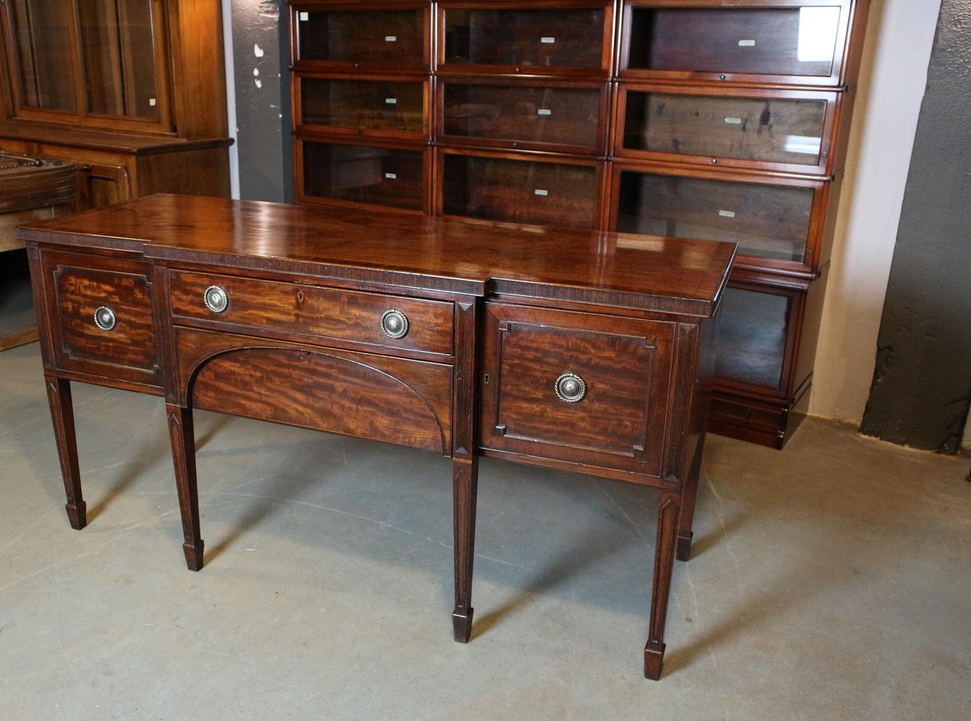 Beautifully mahogany Georgian sideboard. Entirely in original condition. Beautiful patina. The table has 2 drawers in the middle and 2 cupboards. It is a break-front model. The right cabinet was used for the wine bottles, therefore the bottom is