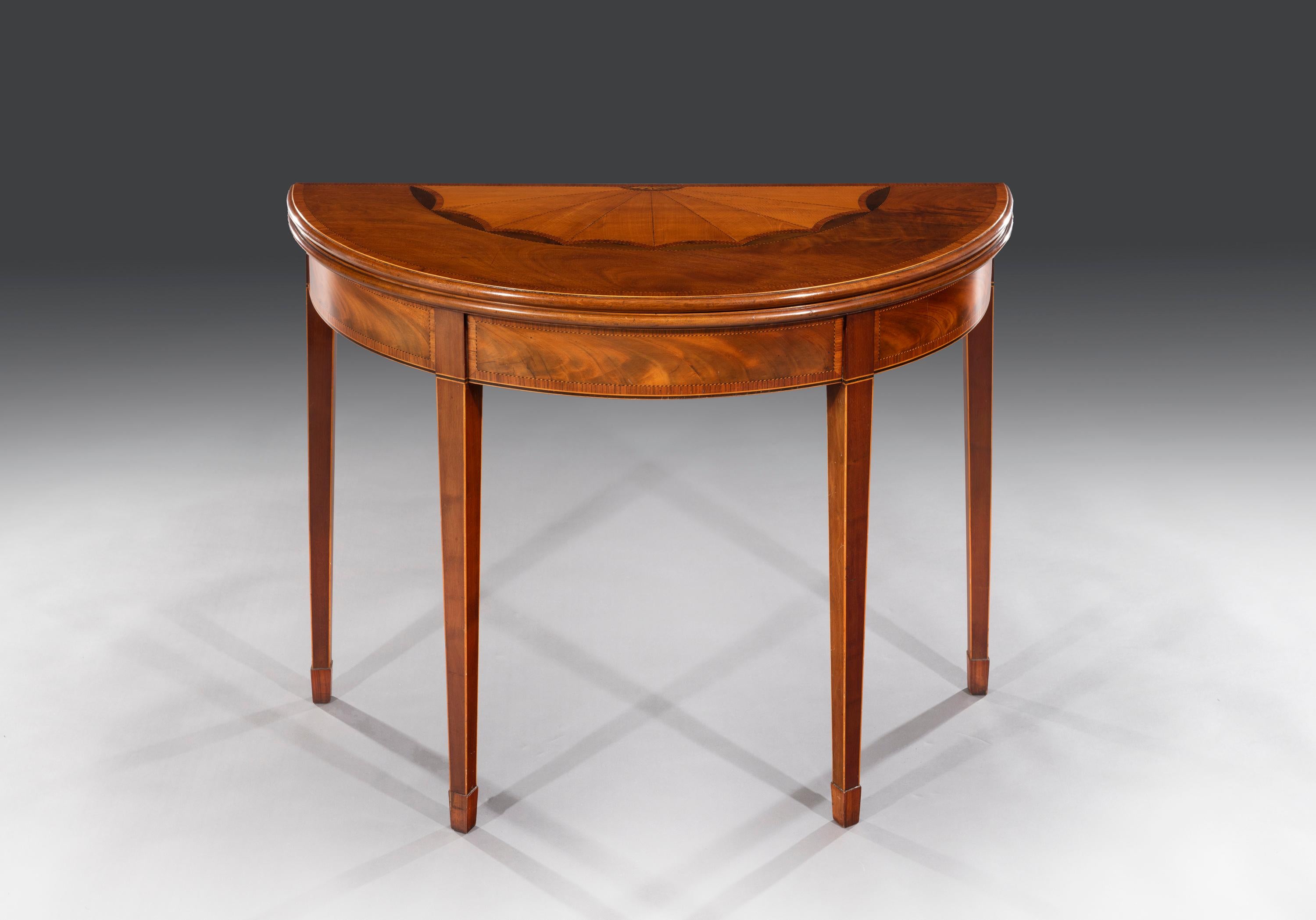 The semi-elliptical top is centred with an impressive satinwood, harewood, boxwood and ebony shaped fan surmounted on a flamed mahogany veneer. The top opens to reveal well figured mahogany and sits on twin-gate leg supports. The inlaid frieze