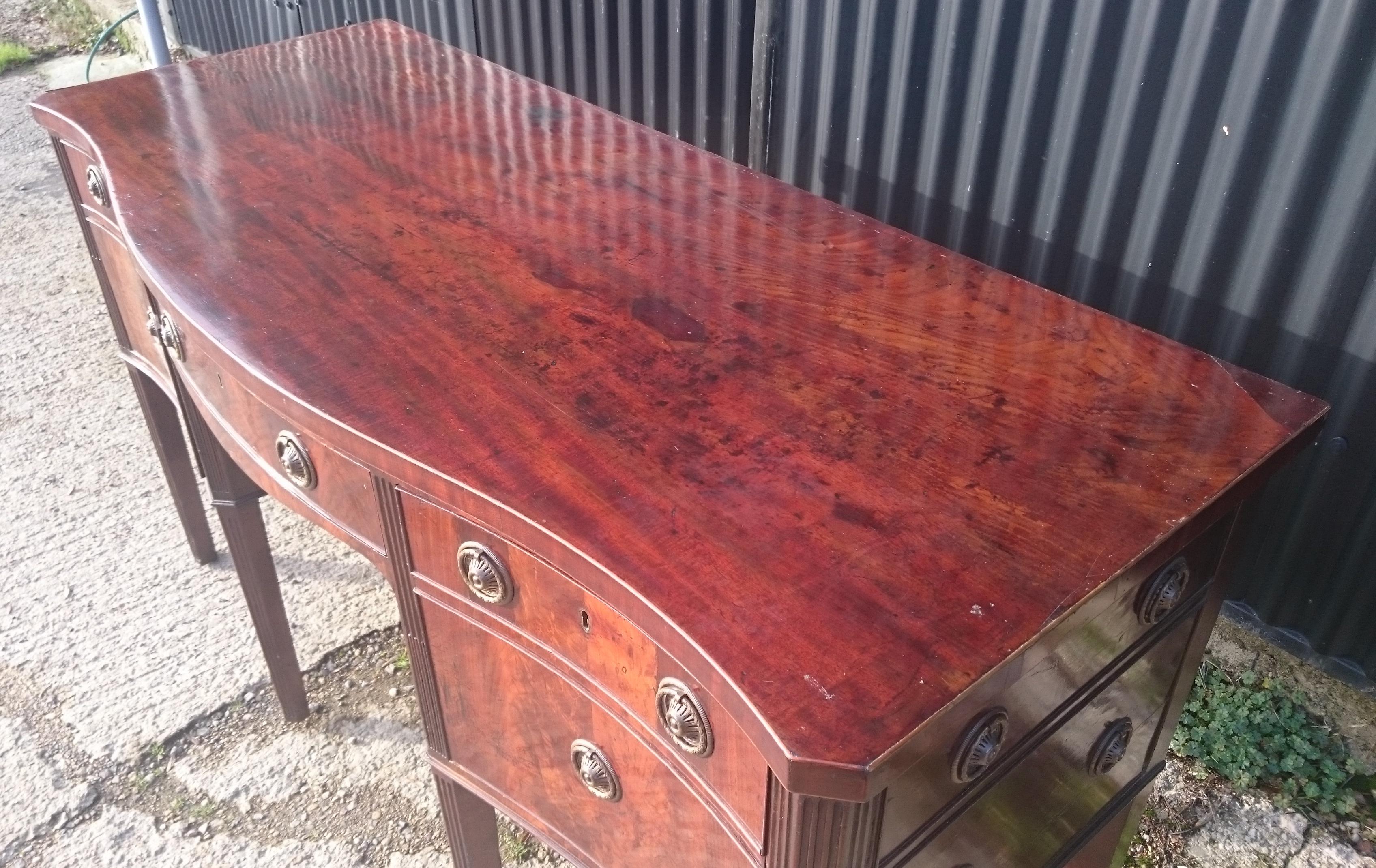 18th century George III period mahogany serpentine fronted sideboard standing on six square reeded legs. This sideboard has been made using a selection of well figured mahogany with flame mahogany used for the drawer fronts. The top is made from a