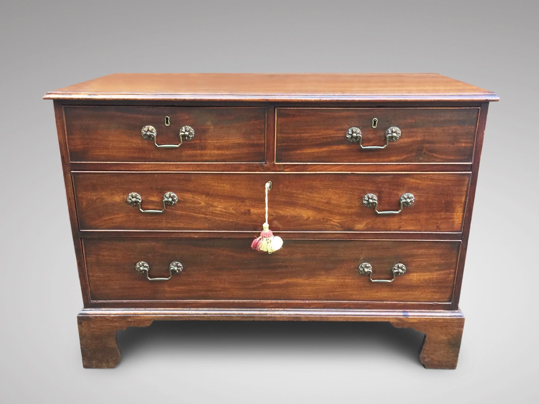 A late 18th-century George III period mahogany chest of drawers featuring a rectangular cross-banded top with a moulded edge. The chest includes two small drawers and two long, graduated, oak-lined drawers, each fitted with the original carved brass