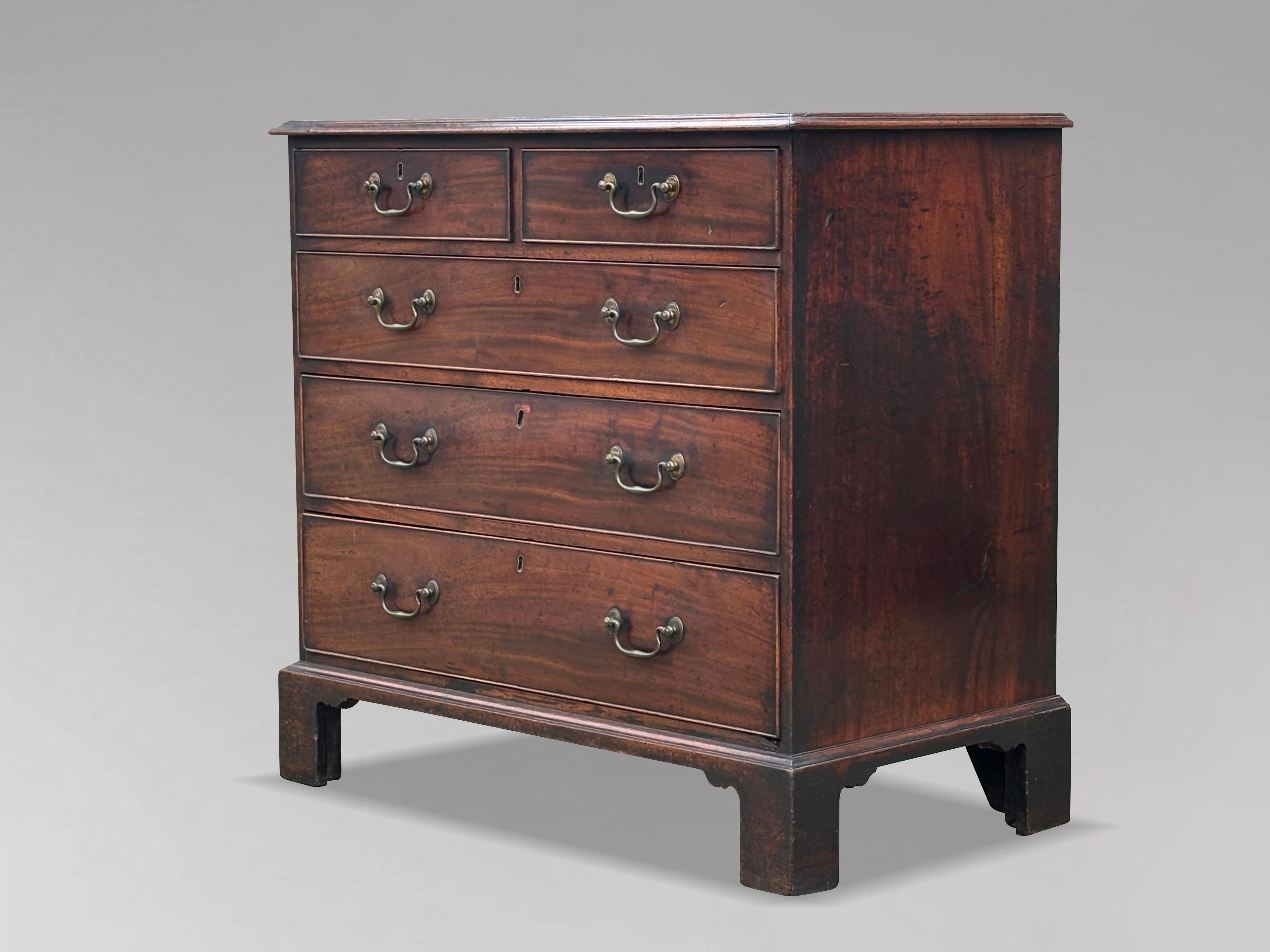 Un'incantevole cassettiera in mogano del tardo XVIII secolo, risalente al periodo di Giorgio III. Presenta un piano rettangolare sagomato a fasce incrociate intarsiate che sovrasta due cassetti corti e tre lunghi graduati rivestiti in rovere, ognuno