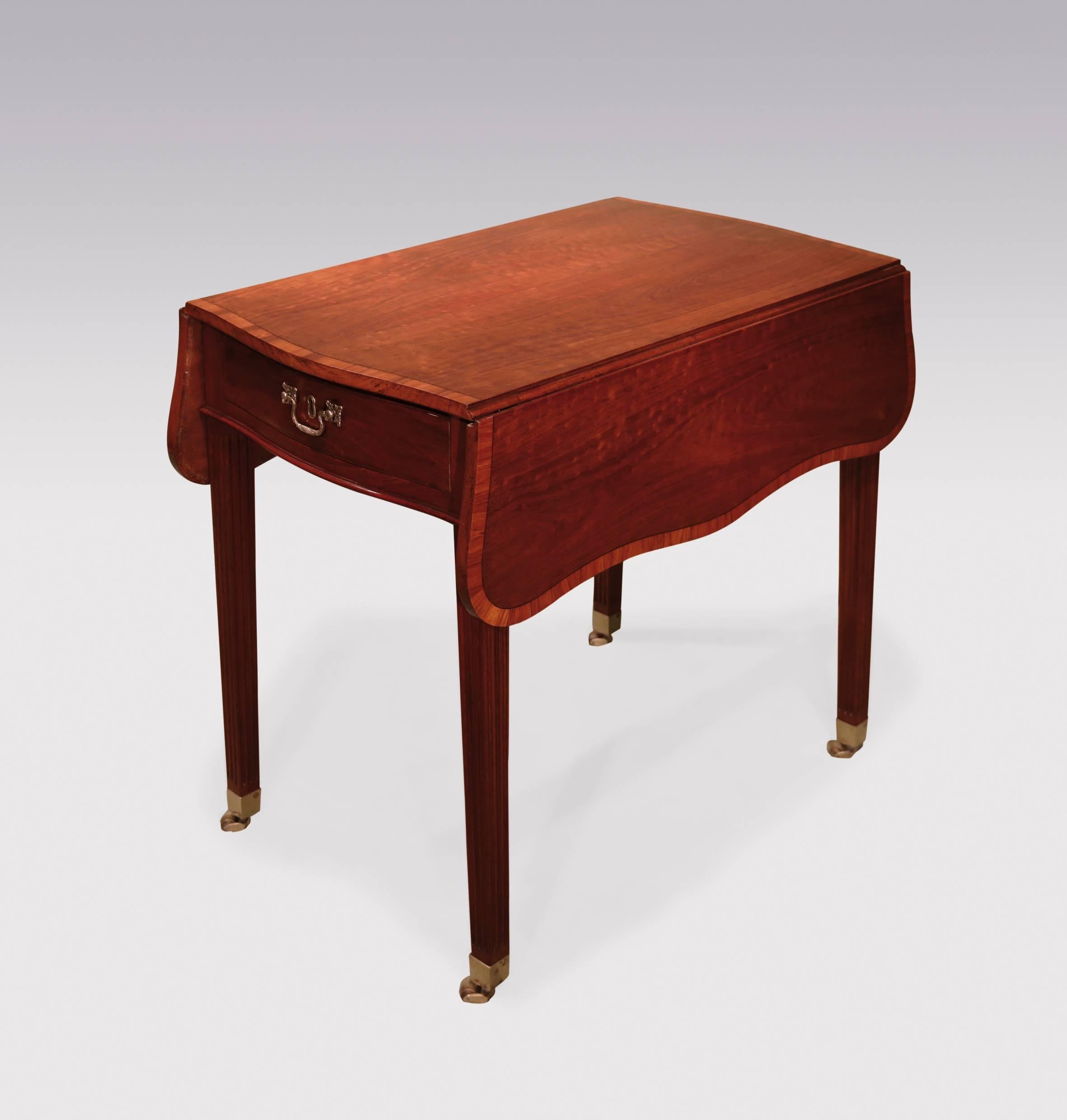 A mid-18th century George III period plum-pudding mahogany Pembroke Table, having padauk wood crossbanded serpentine top, above frieze drawer, supported on fluted square legs, ending on original brass castors. Flaps down: 20ins (51cms)