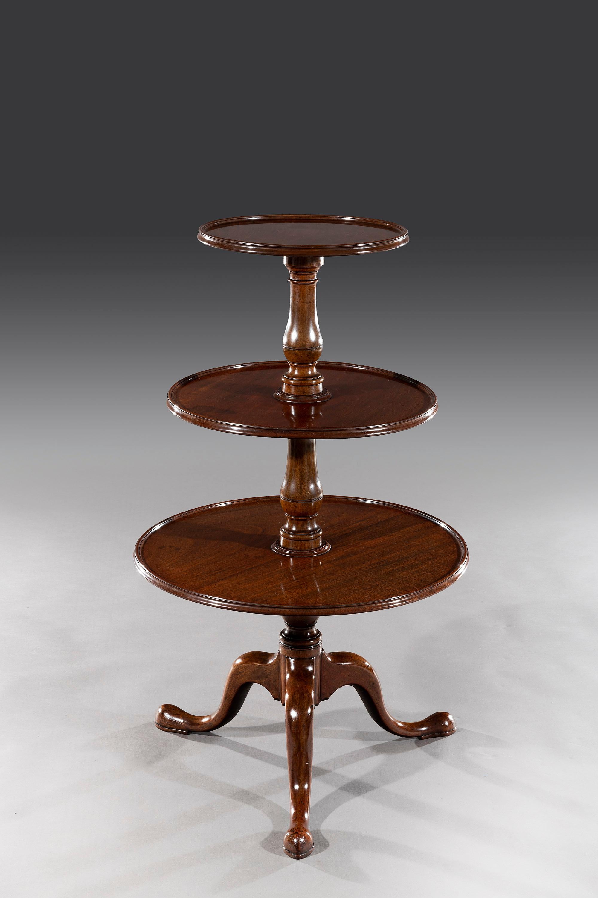 The three solid mahogany circular tiers are graduated and fitted to a turned column. Each tier rotates freely and the dumbwaiter stands on a bulbous shaped pedestal above elegant down-swept legs that sit on pad feet and brass castors.