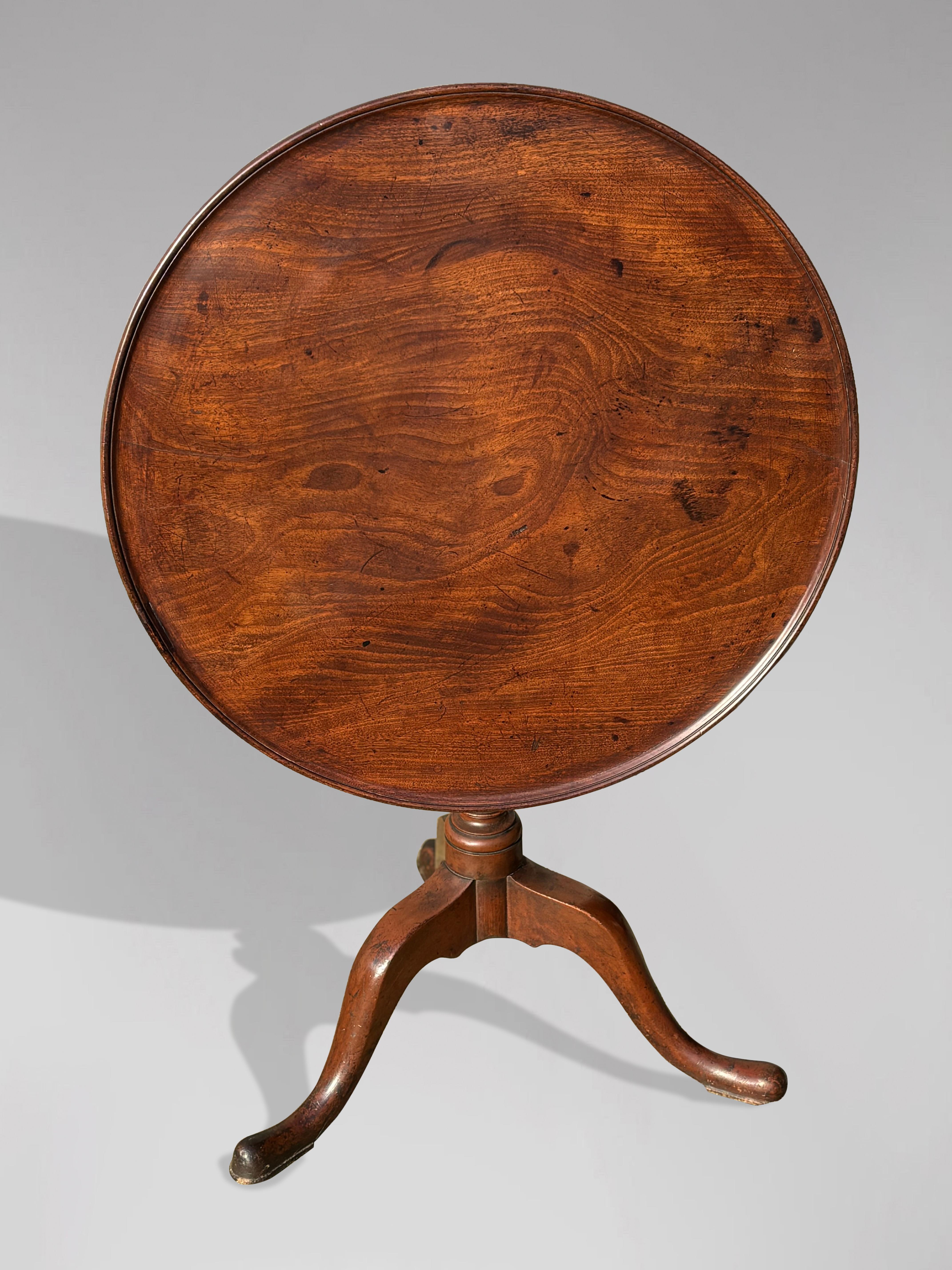 Une belle table tripode en acajou de la fin du XVIIIe siècle, d'époque George III, avec un bord mouluré en relief. Le plateau circulaire basculant est constitué d'une seule pièce d'acajou massif bien dessinée, au-dessus d'une colonne tournée en