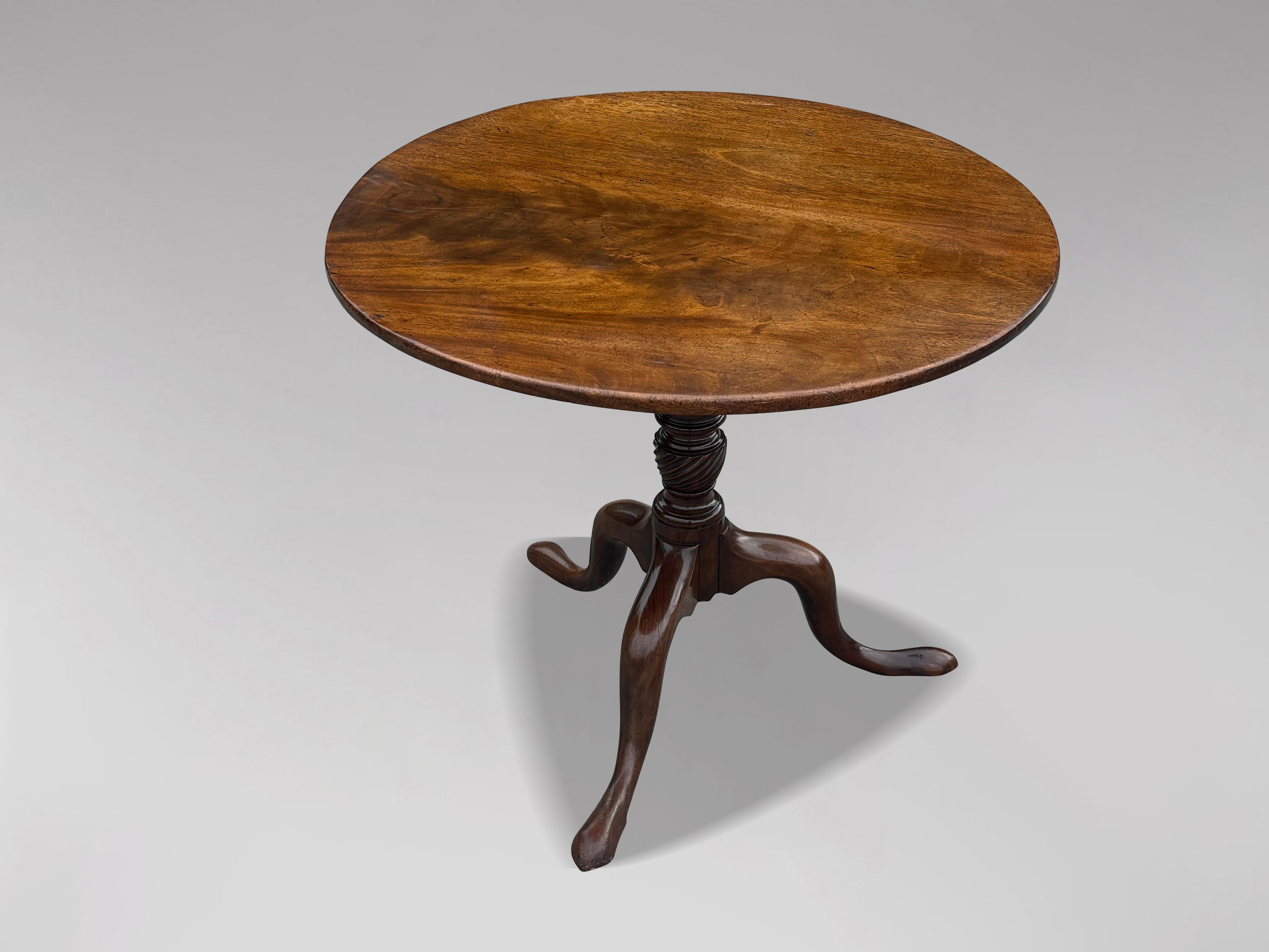 Magnifique table tripode en acajou de la fin du XVIIIe siècle, d'époque George III. Le plateau circulaire basculant est constitué d'une seule pièce d'acajou massif bien sculptée, au-dessus d'une colonne tournée en forme de balustre. Cette table