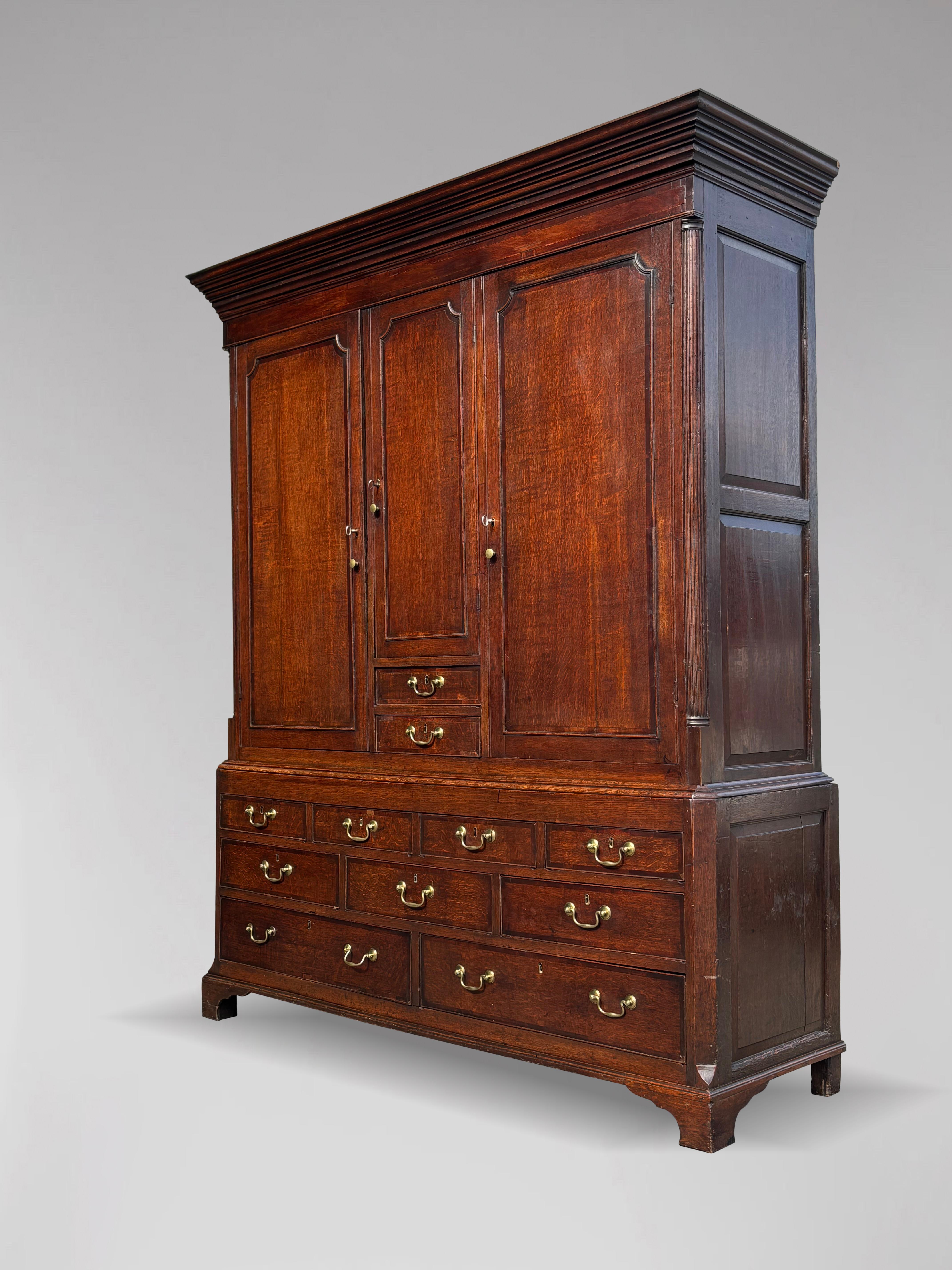 A fine quality antique late 18th-century George III period English oak housekeeper's cupboard or livery cupboard. The cupboard features an elegant protruding cavetto cornice below a solid boarded top. It is divided into three sections. The cornice