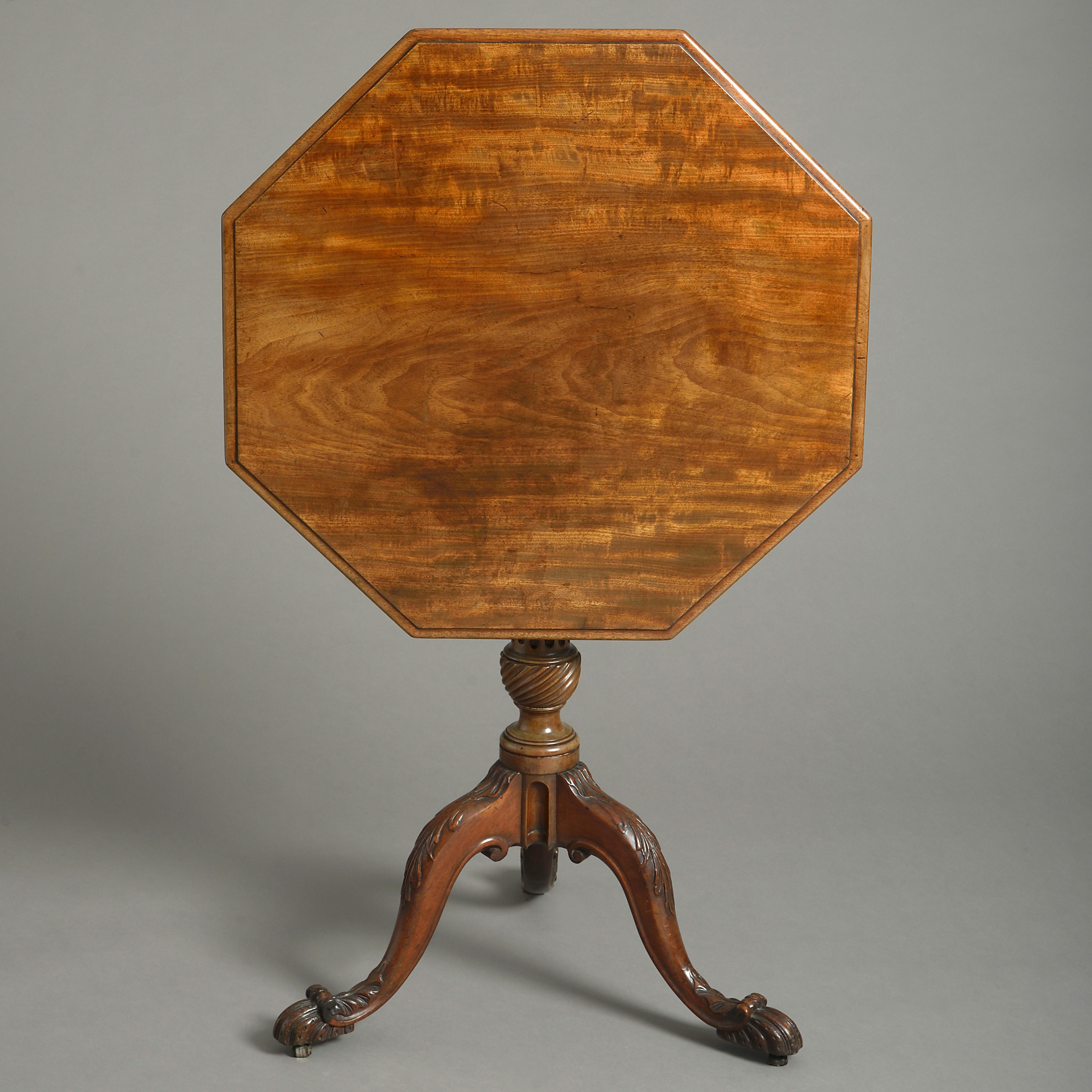 A George III period Thomas Chippendale style mahogany tripod table, having an octagonal figured top upon a turned fluted column stem with spiral base, all terminating in three cabriole legs with richly carved acanthus decoration and scrolling feet