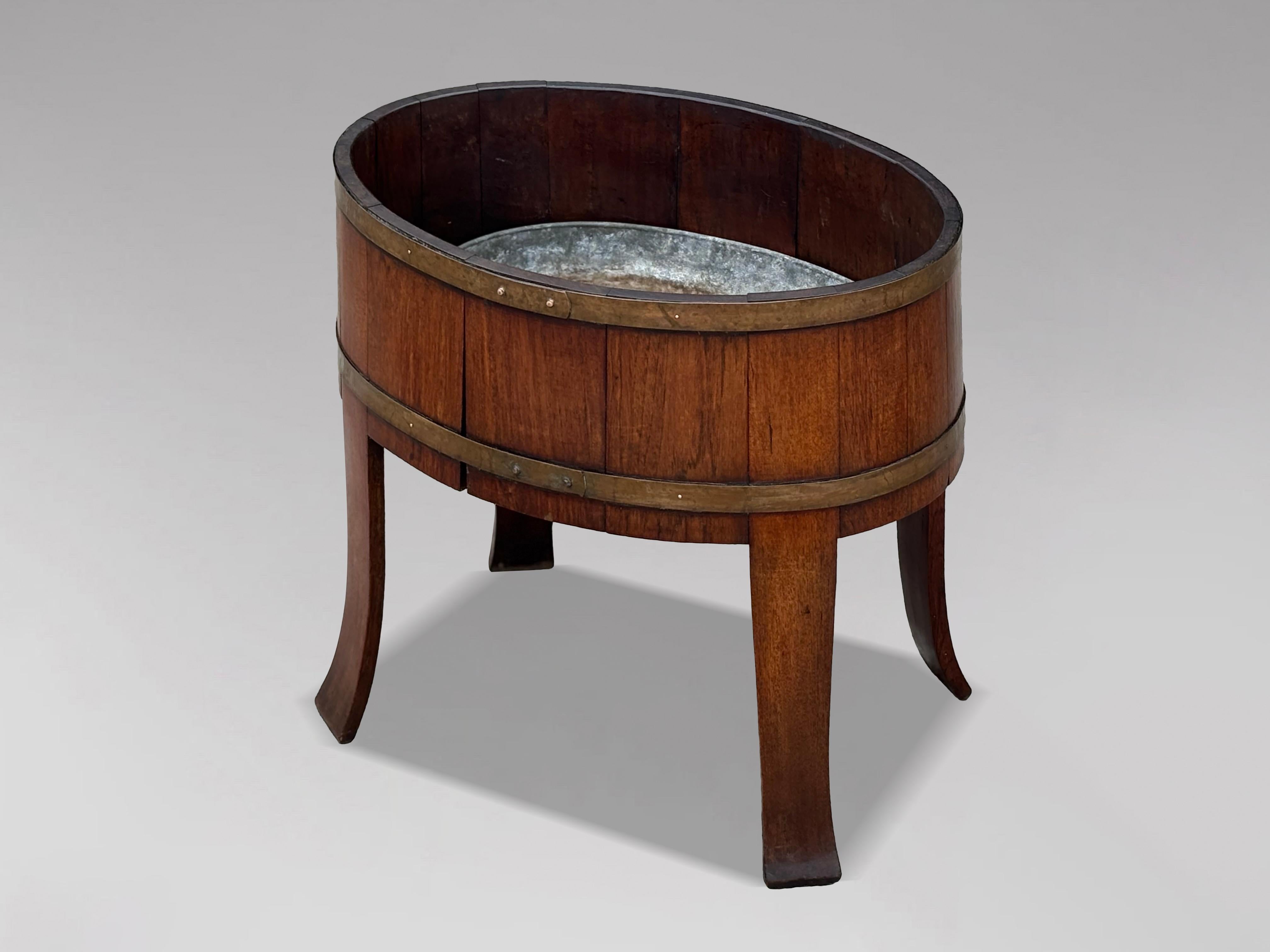 A fine Georgian Walnut Brass-Bound Oval Wine Cooler or Jardinière

A fine Georgian oval wine cooler or jardinière in richly figured walnut, coopered and bound with deep brass bands. Resting on well-proportioned sabre legs, this example reflects the