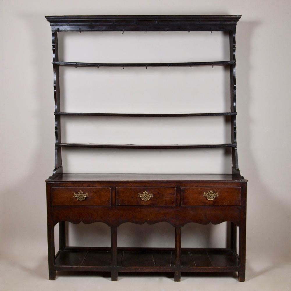 A delightful, small, late 18th century oak dresser and rack of the most wonderful colour. With its original rack, which retains its original hand forged iron hooks, the shelves have bowed over time and are beautifully sculptural. The pot board base,