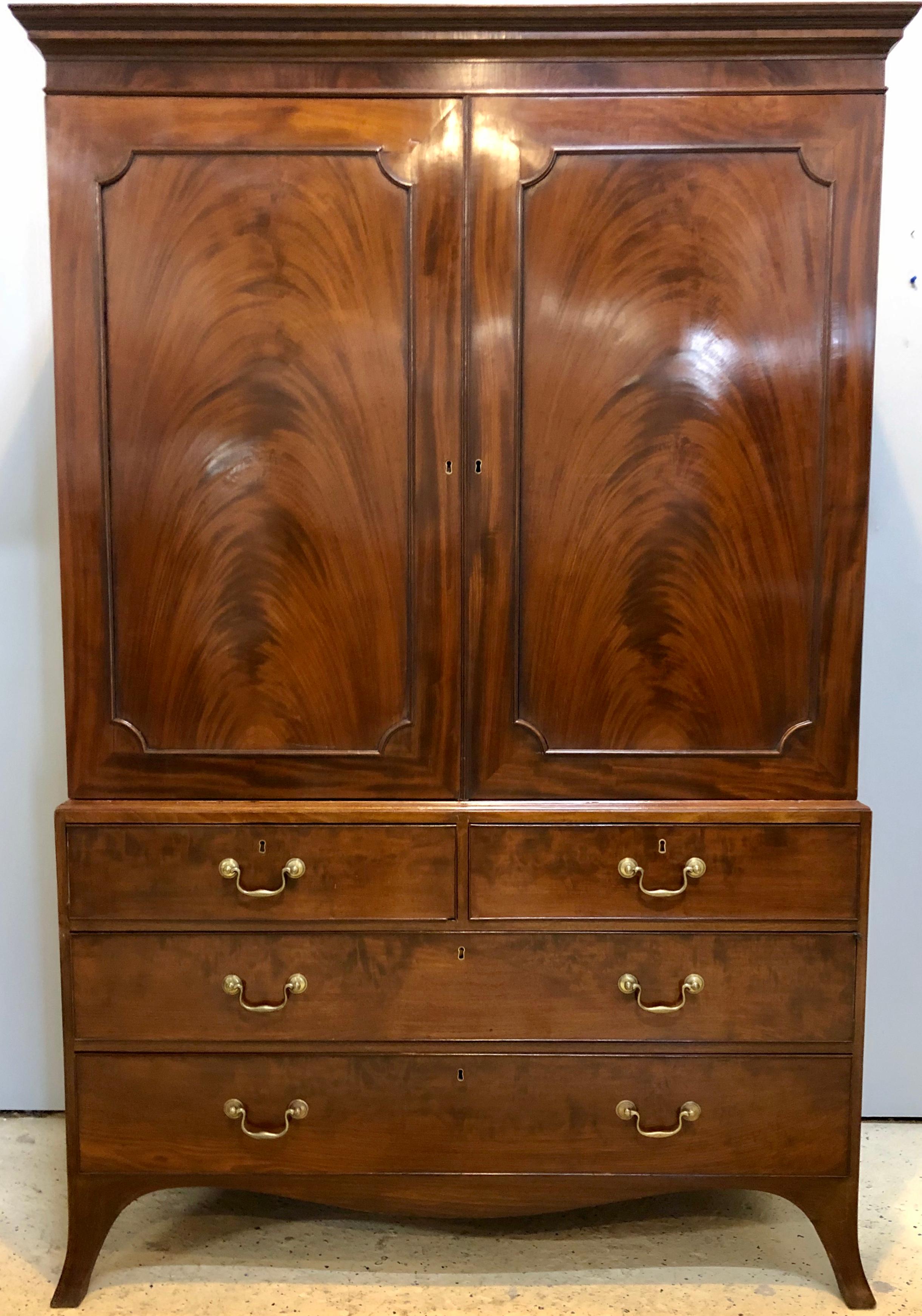 18th century George III linen press in mahogany. Having two over three drawers on the bottom commode on its original legs with an upper case of two doors leading to an open compartment. This item is priced to be sold immediately. No interior