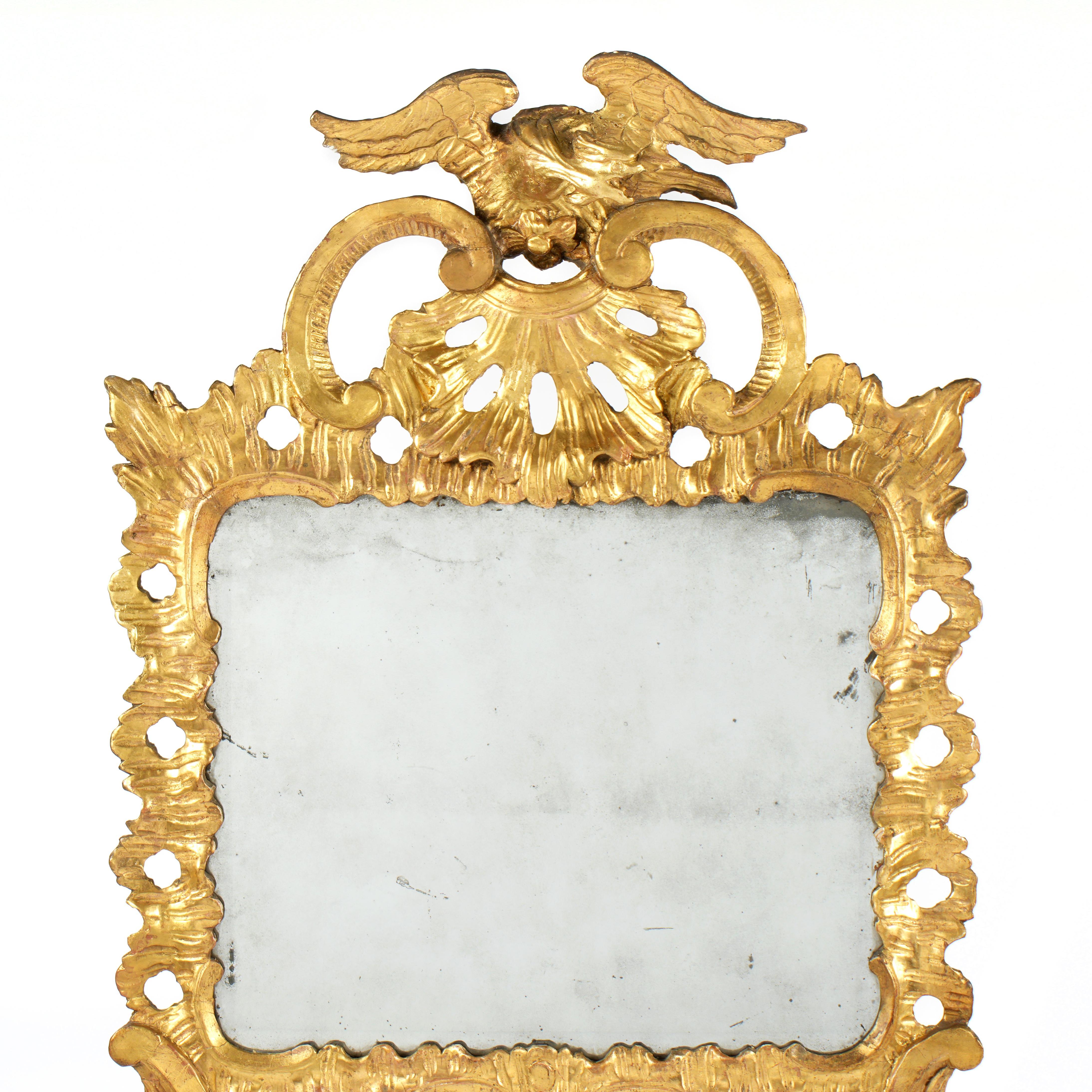 Miroir mural en bois doré sculpté de style géorgien du XVIIIe siècle. Le miroir est orné d'un aigle figuratif aux ailes déployées, symbole éminent de puissance, de majesté et de liberté, et motif favori de l'art géorgien. L'aigle trône fièrement