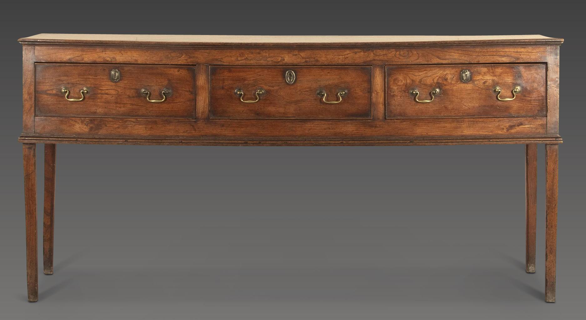 A well desired 18th Century elm dresser of elegant proportions.
The well figured top above three drawers with original brass swan neck handles and raised on the original tall elm legs. Circa 1760. 
In overall good condition with no noticeable damage