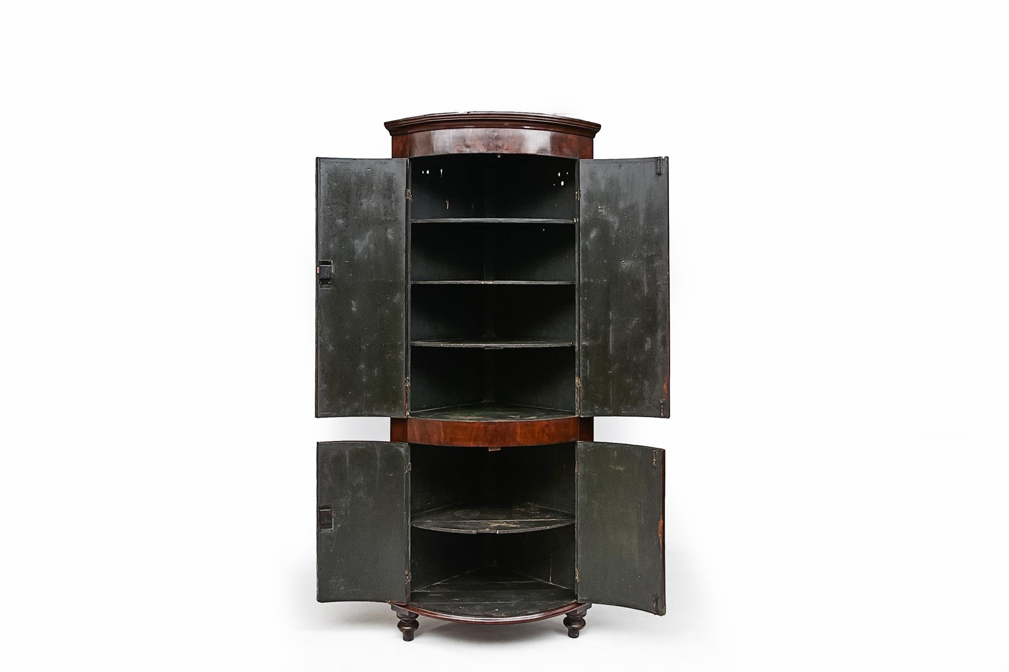 18th century Georgian flame mahogany bowfront/ barrel corner cabinet, the moulded cornice above four cockbeaded doors with satinwood line inlay, reeded brass closing slip with brass escutcheons, the top two blind doors revealing four shelves, the