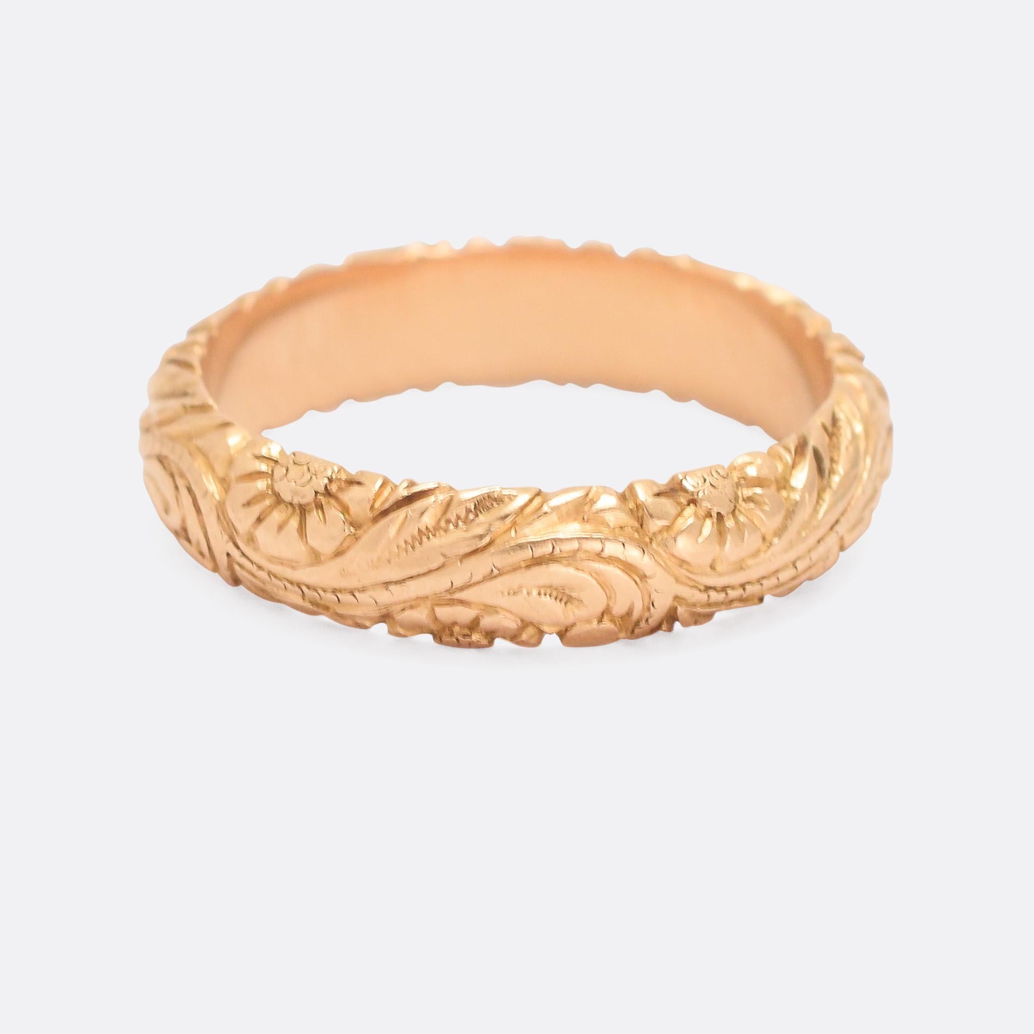 A stunning 18th Century gold band adorned with deeply chased rose motifs. It's crafted in 18 karat gold and dates from the 1750s; the quality is particularly good, and it has a substantial feel at 10.5g in weight. The carving is well executed and