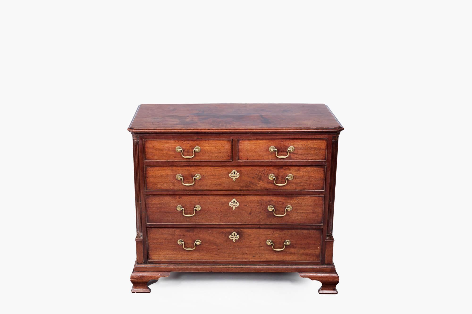 18th century Georgian mahogany chest of drawers. It features two smaller drawers above three full-length drawers with original brass swan neck handles and decorative brass escutcheons on the lower drawers. Carved fluted pillars, in the classical